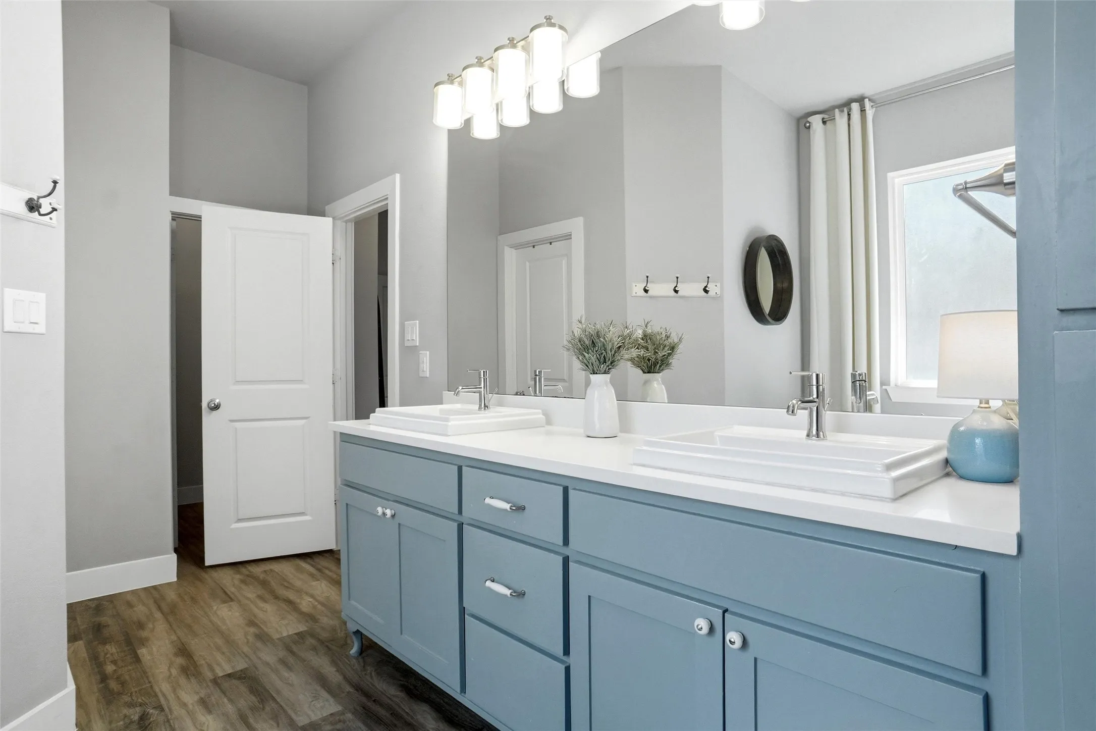 The master bathroom vanity reflecting the dual sinks, cabinet style vanity,  and rich flooring.
