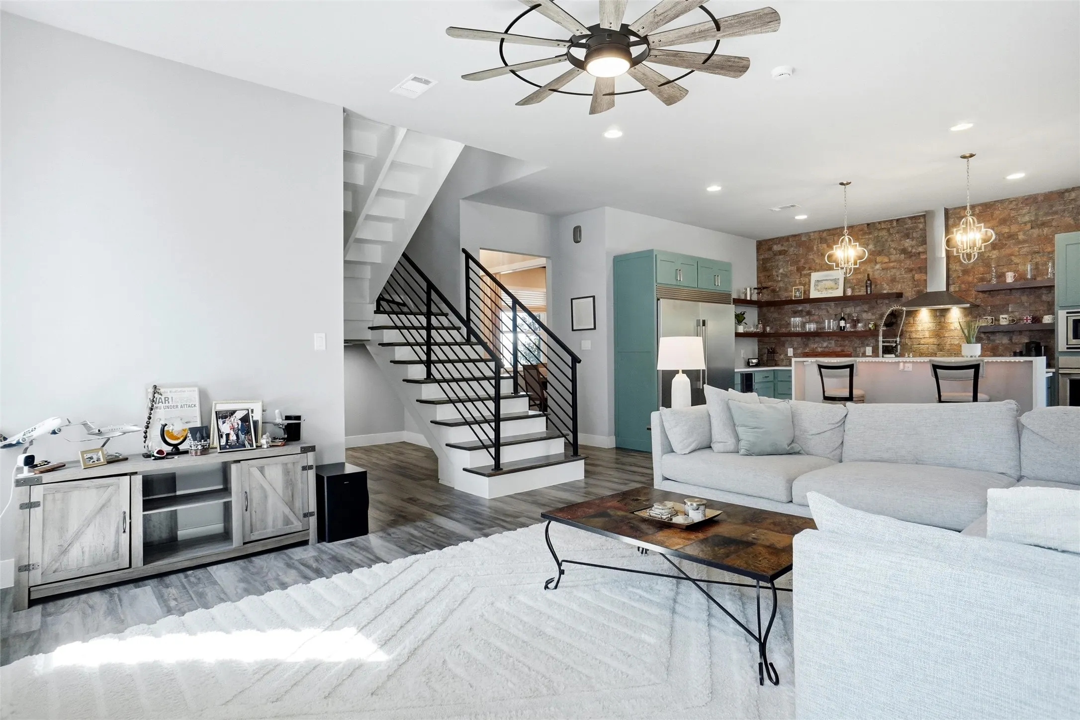 This view shows the cubby under the stairs (actually looks larger in person), the dining room behind the staircase, and the open floor plan with the kitchen. The floor looks a little grey by the cabinet in the living room...this is an optical illusion. It is the same rich floor throughout as seen in the prior photos.