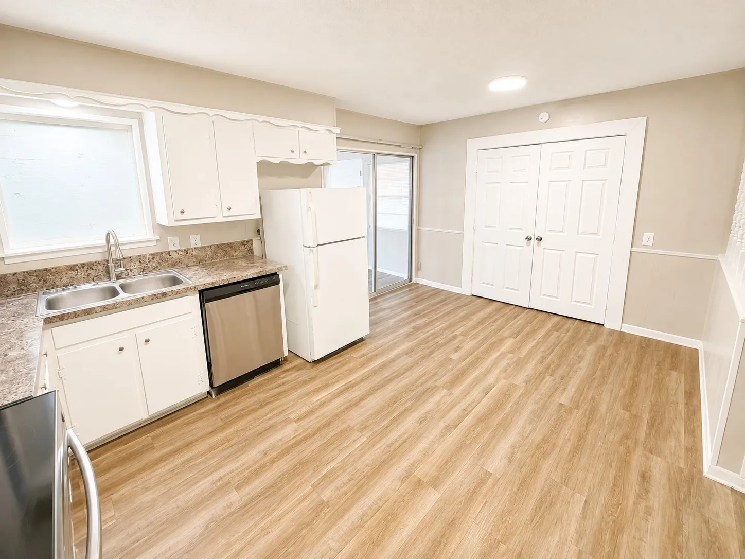White cabinetry with integrated stainless steel dishwasher, dual basin sink, and wood-finish flooring