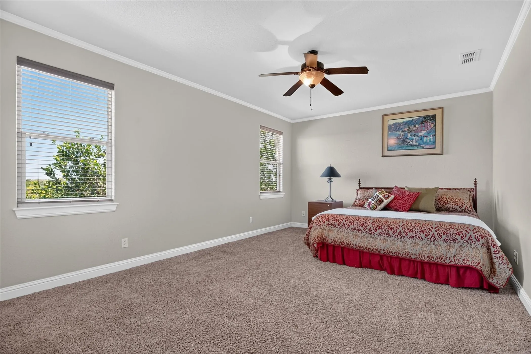 Carpeted flooring, two windows with blinds, ceiling fan, and crown molding