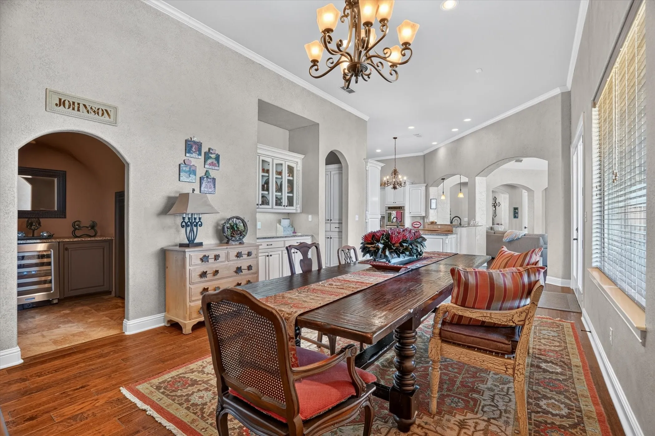Hardwood flooring, arched doorways, crown molding, built-in cabinetry, and a wine refrigerator