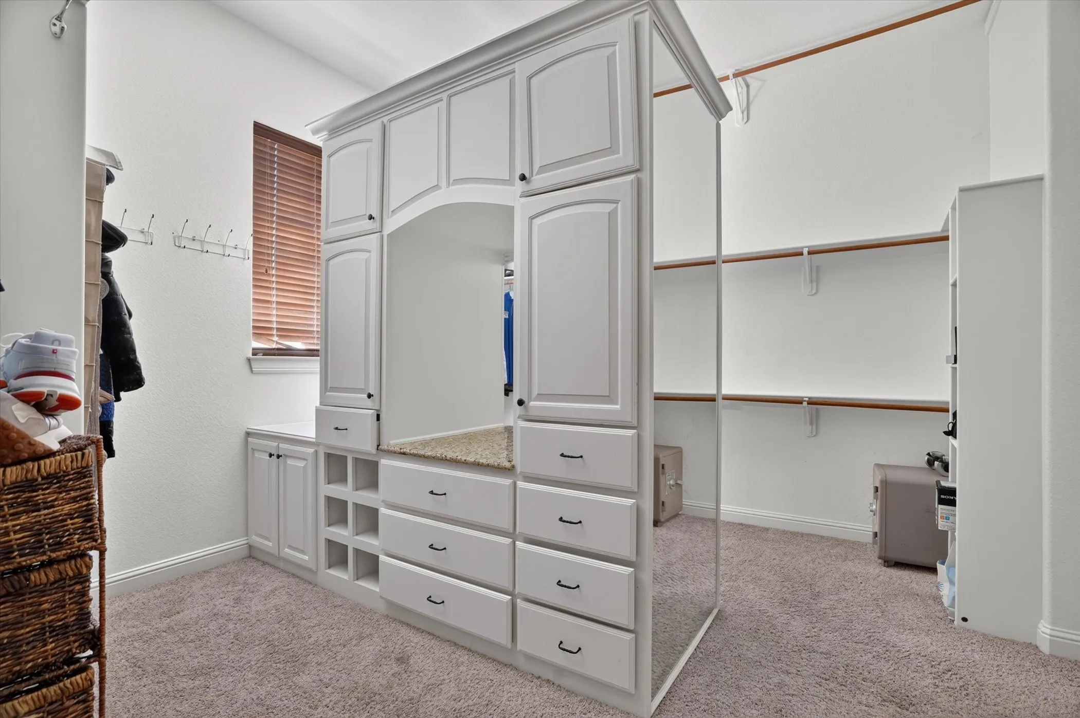 Custom walk-in closet featuring built-in cabinetry with mirrored doors, multiple drawers with brushed-metal hardware, open shelving, and carpeted flooring throughout