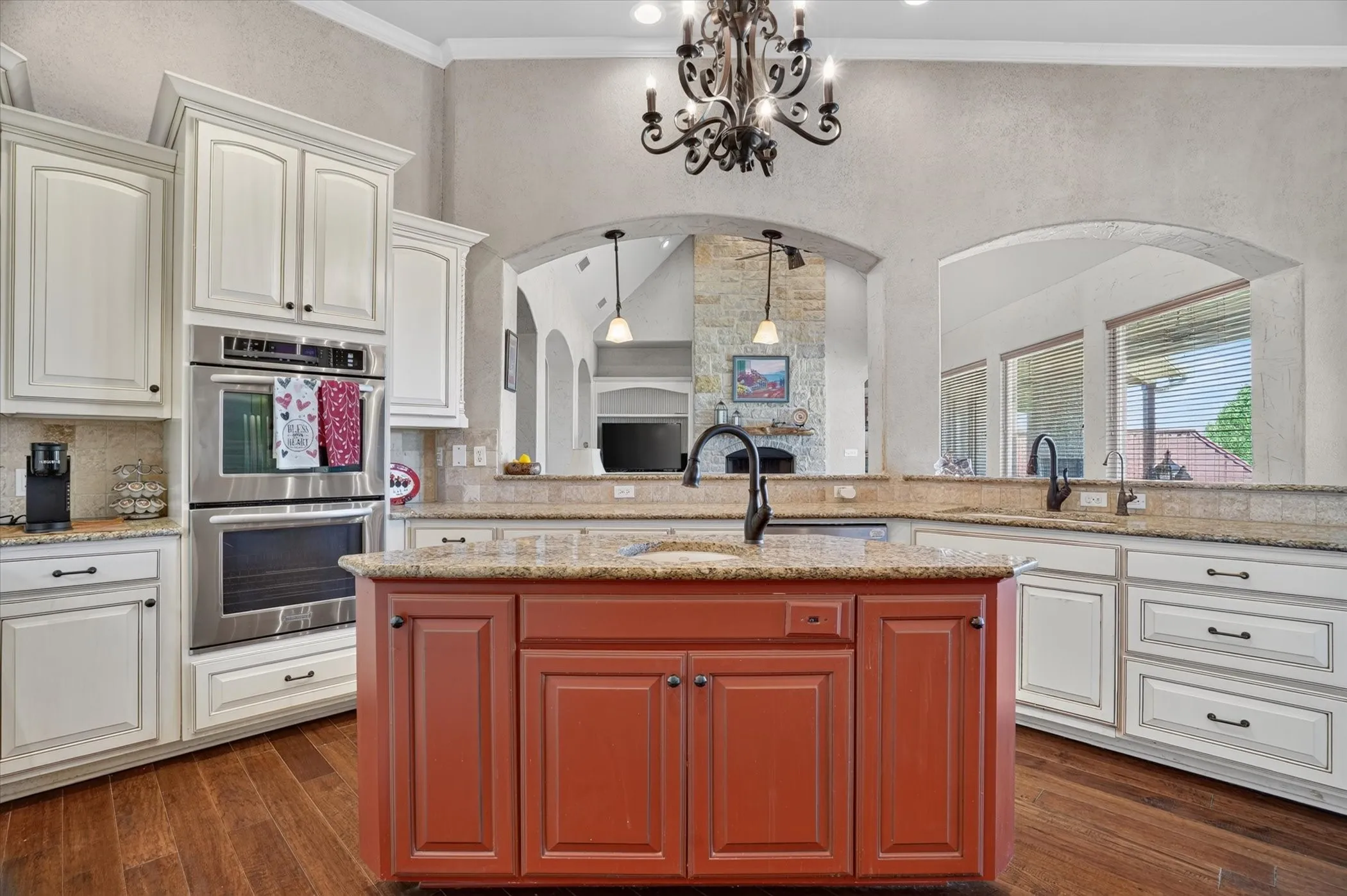 Kitchen featuring a central island, wood-finish flooring, white cabinetry, stainless steel double ovens, and granite countertops