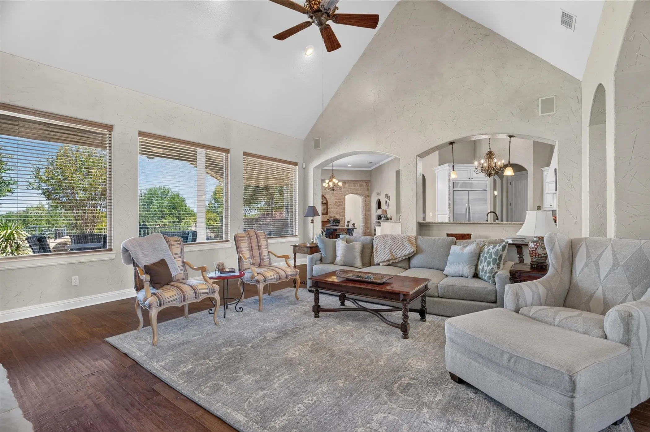 Vaulted ceiling with a ceiling fan, recessed lighting, wood-finish flooring, multiple windows with horizontal blinds, and arched doorways