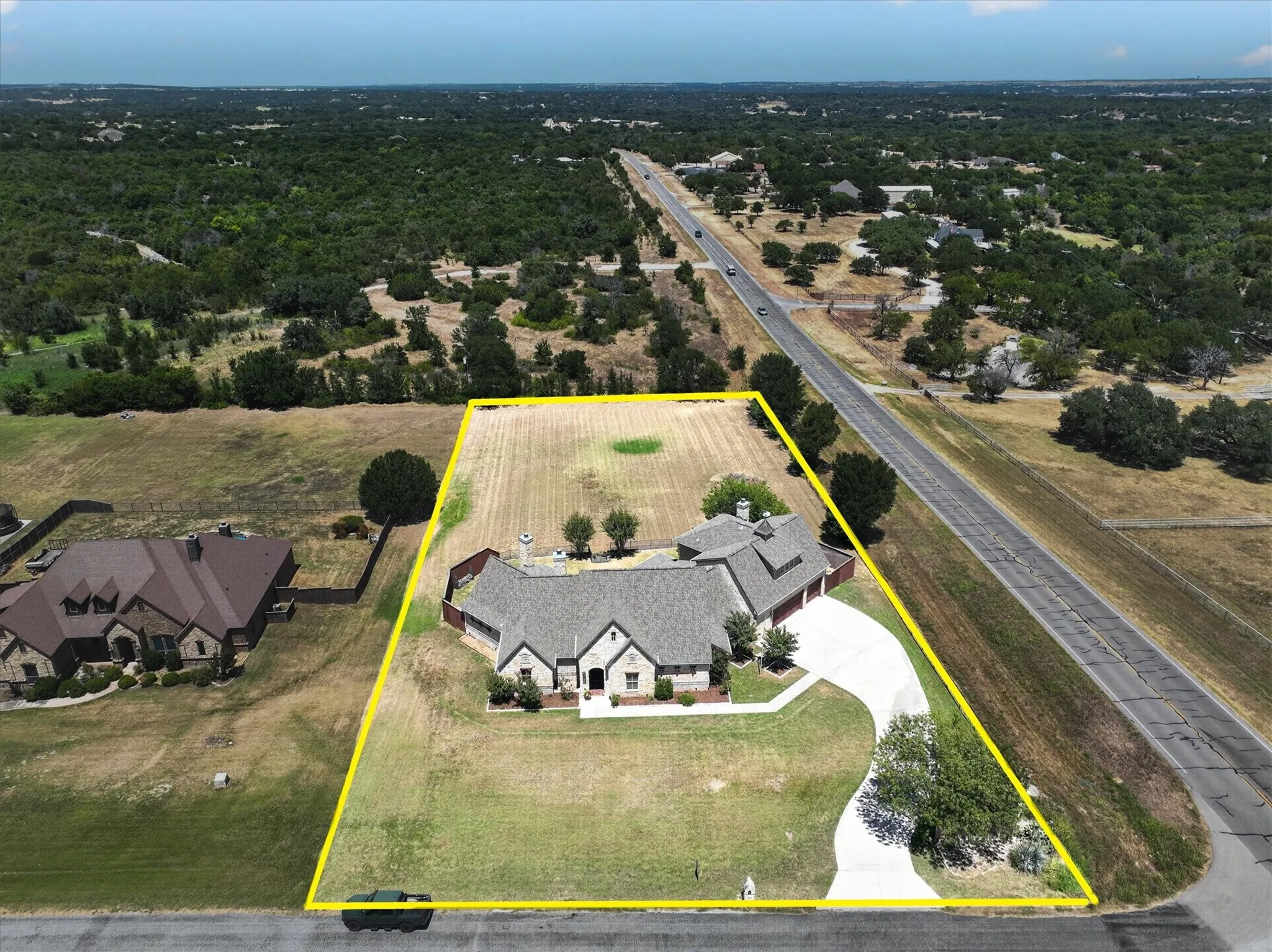 Expansive property featuring a stone and brick exterior, multi-gabled roofline, attached garages, and a curved paved driveway