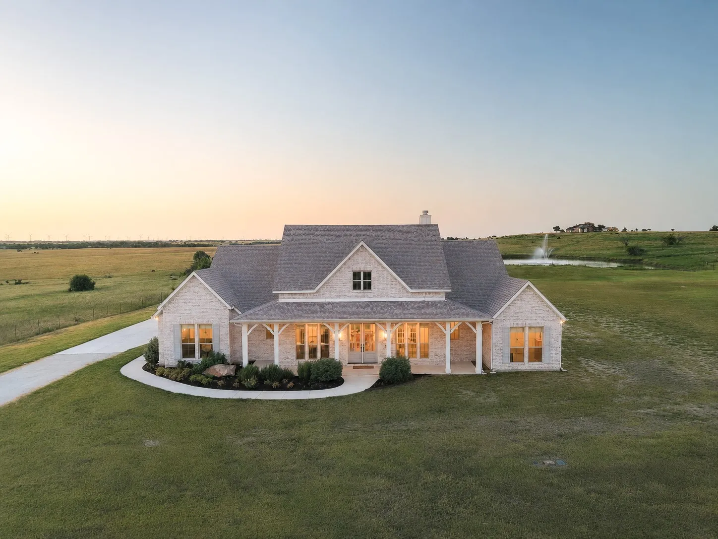 Expansive property featuring a stone exterior, covered front porch, gabled roofline, and a paved driveway