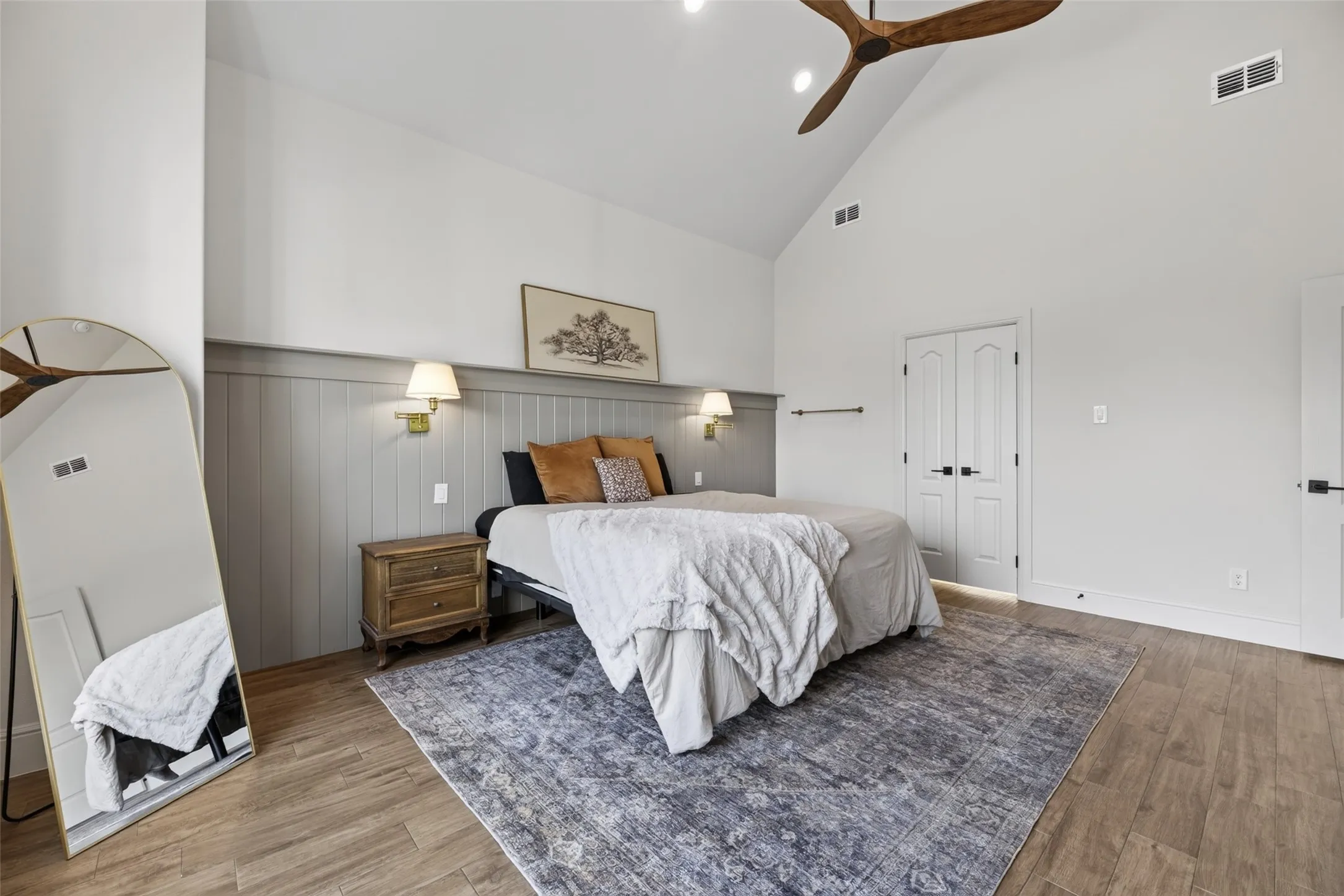 Vaulted ceiling with a wood-finish ceiling fan, board and batten wall accent, wood-finish flooring, and white paneled doors