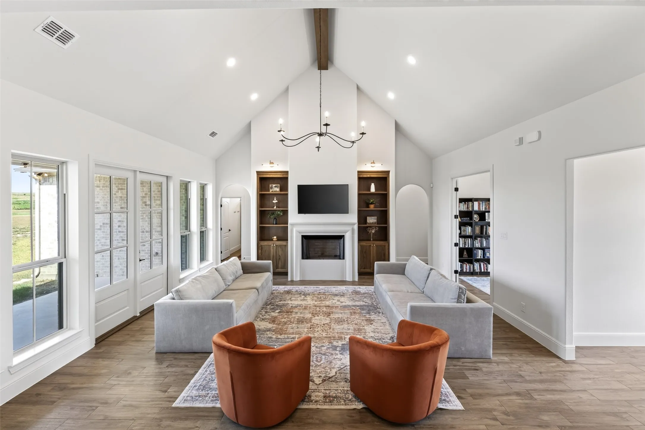 Vaulted ceiling with exposed wood beam, recessed lighting, and a chandelier