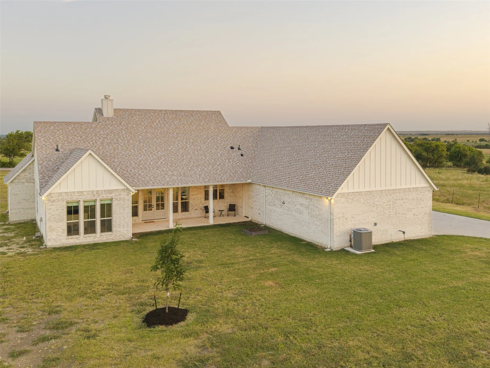 White brick exterior with a covered porch, multiple windows, and an asphalt shingle roof