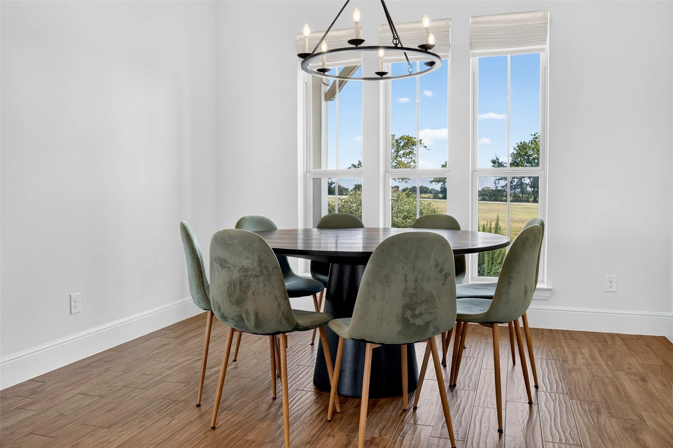 Sophisticated dining room featuring a round black table, upholstered chairs with wood legs, and hardwood flooring throughout