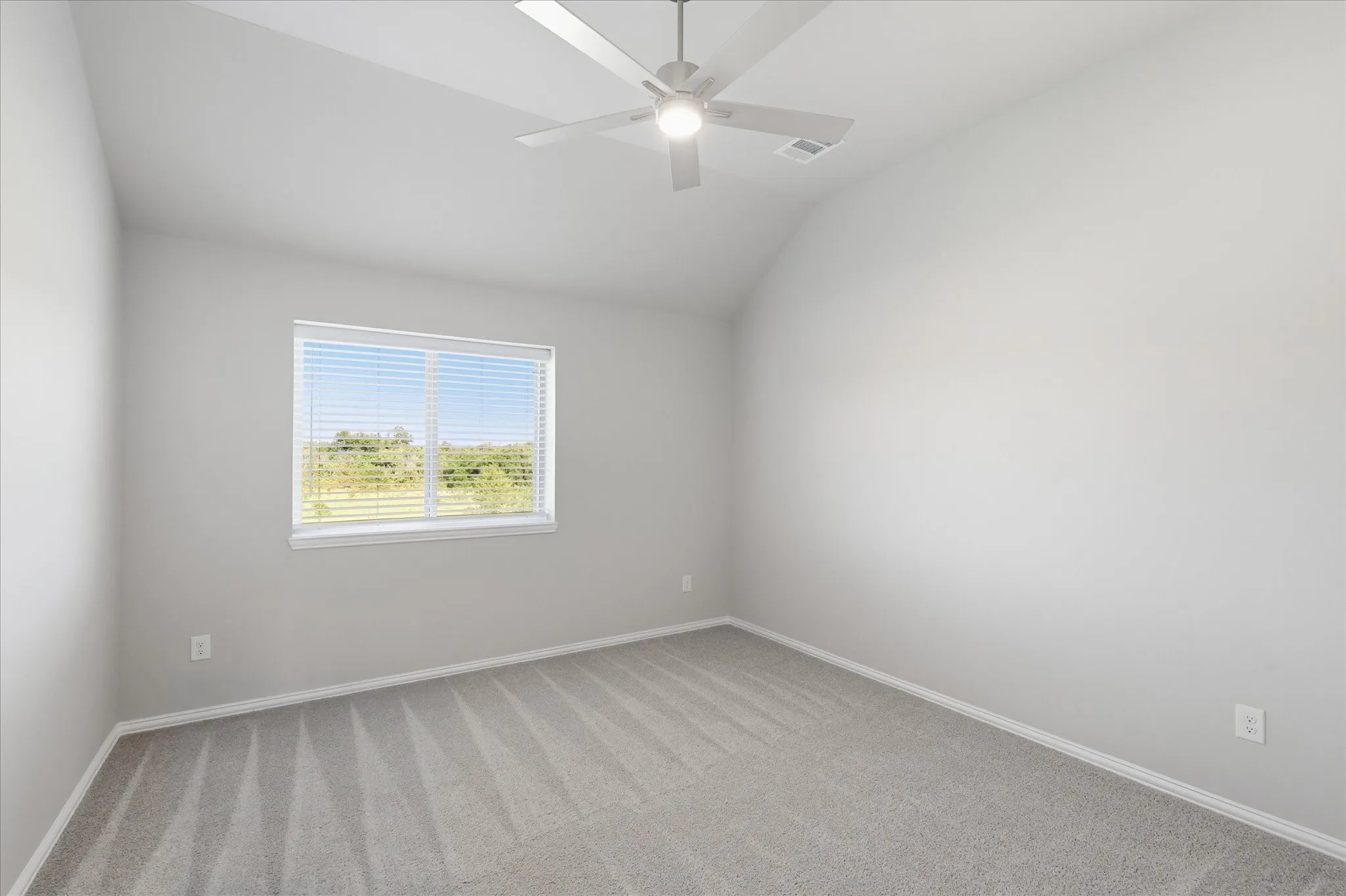Vaulted ceiling, ceiling fan with light, gray carpet flooring, window with horizontal blinds, neutral wall paint! The other two bedrooms match however one has recessed lighting as well!