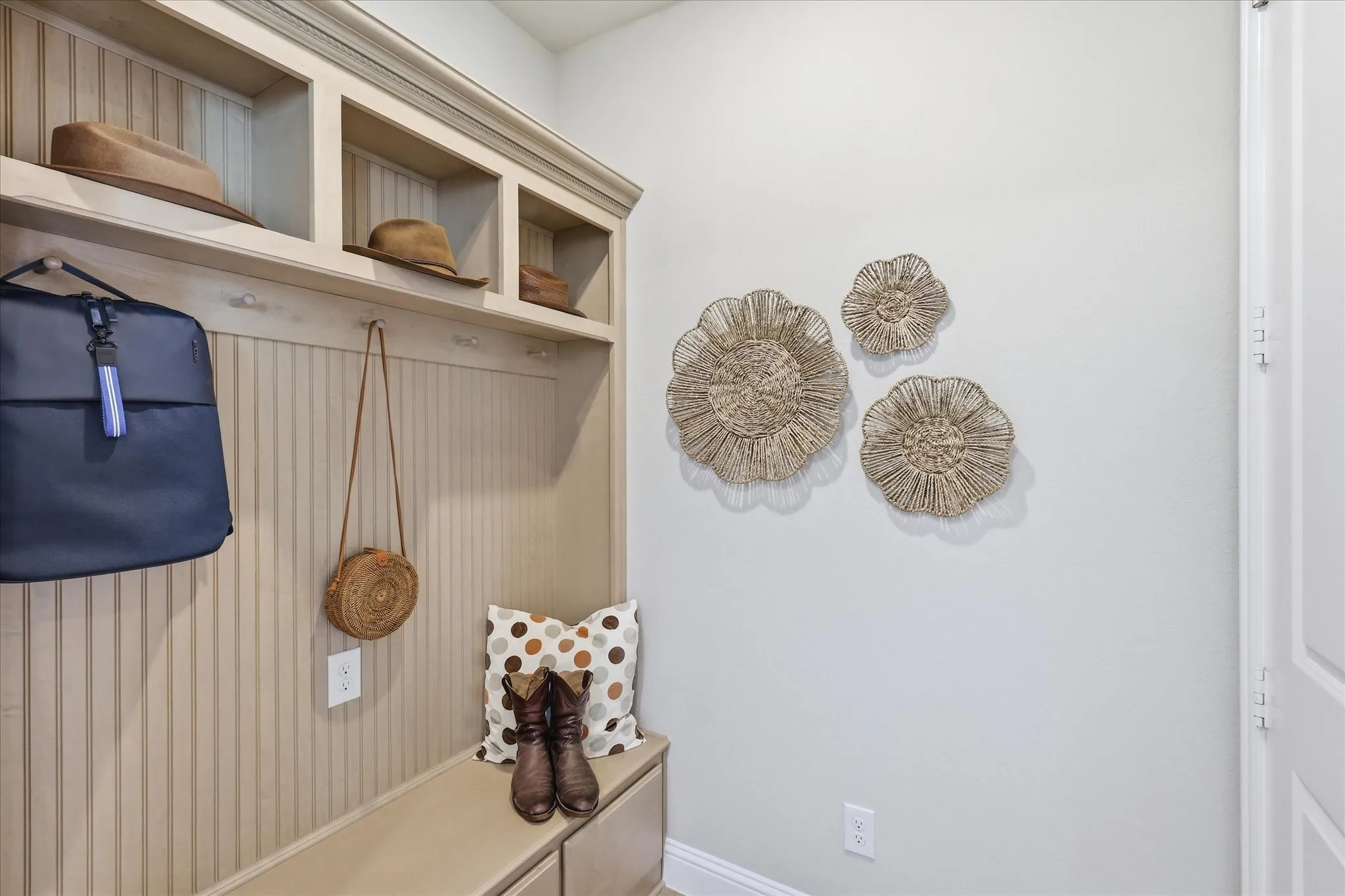 Built-in storage bench with beadboard paneling, upper cubbies, and coat hooks, right by garage entry.