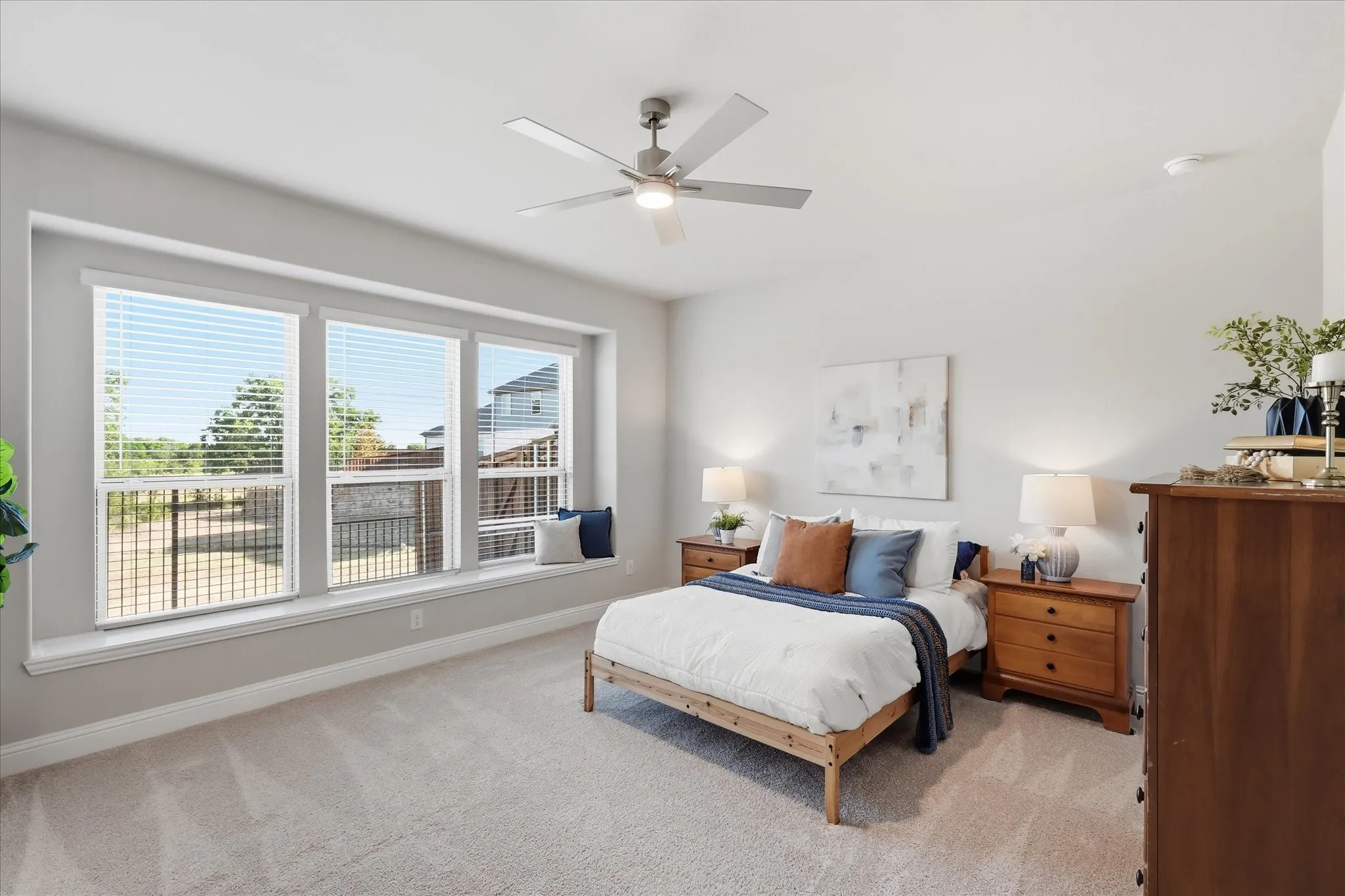 1st floor Primary with recessed window bay with built-in bench seating, multiple large windows with blinds, and light gray wall paint