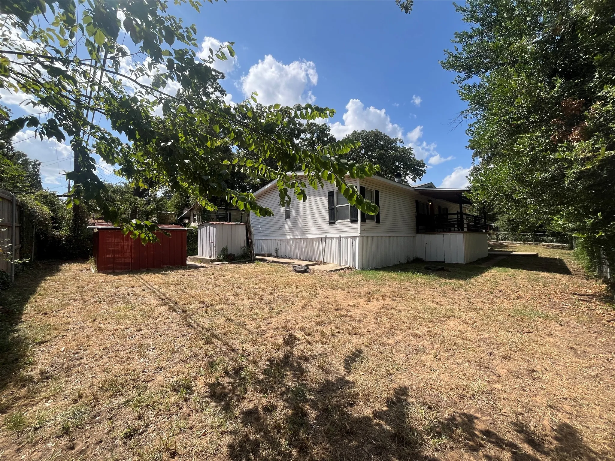 View of large private backyard from 8' wooden fence bordering the back perimeter. Chainlink fence on sides and front.