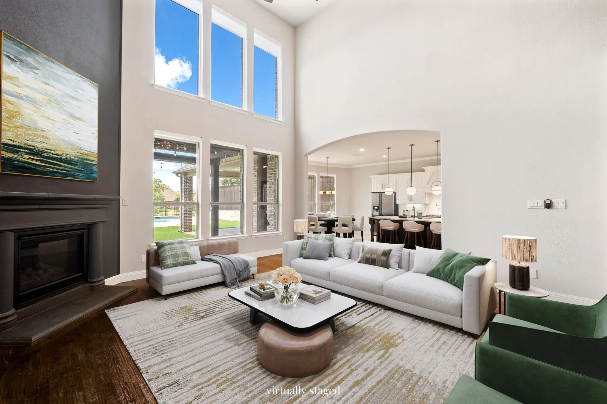 Two-story living area with high ceilings, dark wood-finish flooring, and a fireplace with a dark mantel