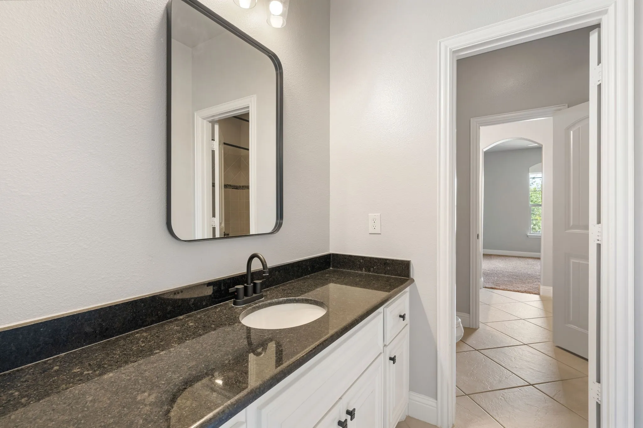 Vanity with dark countertop, undermount sink, and black faucet