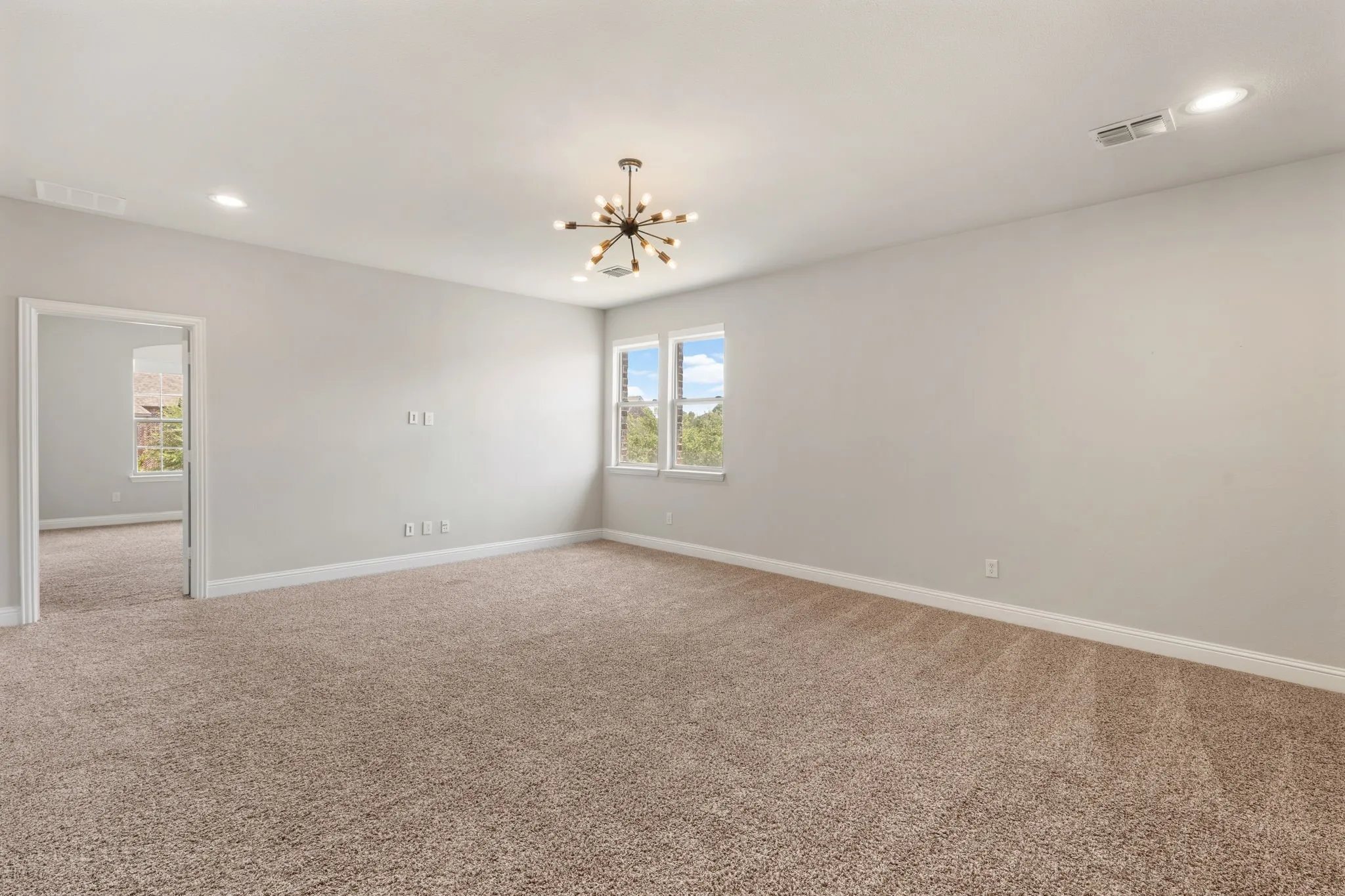 Spacious room featuring neutral carpeting, a modern sputnik chandelier, recessed lighting, and multiple windows