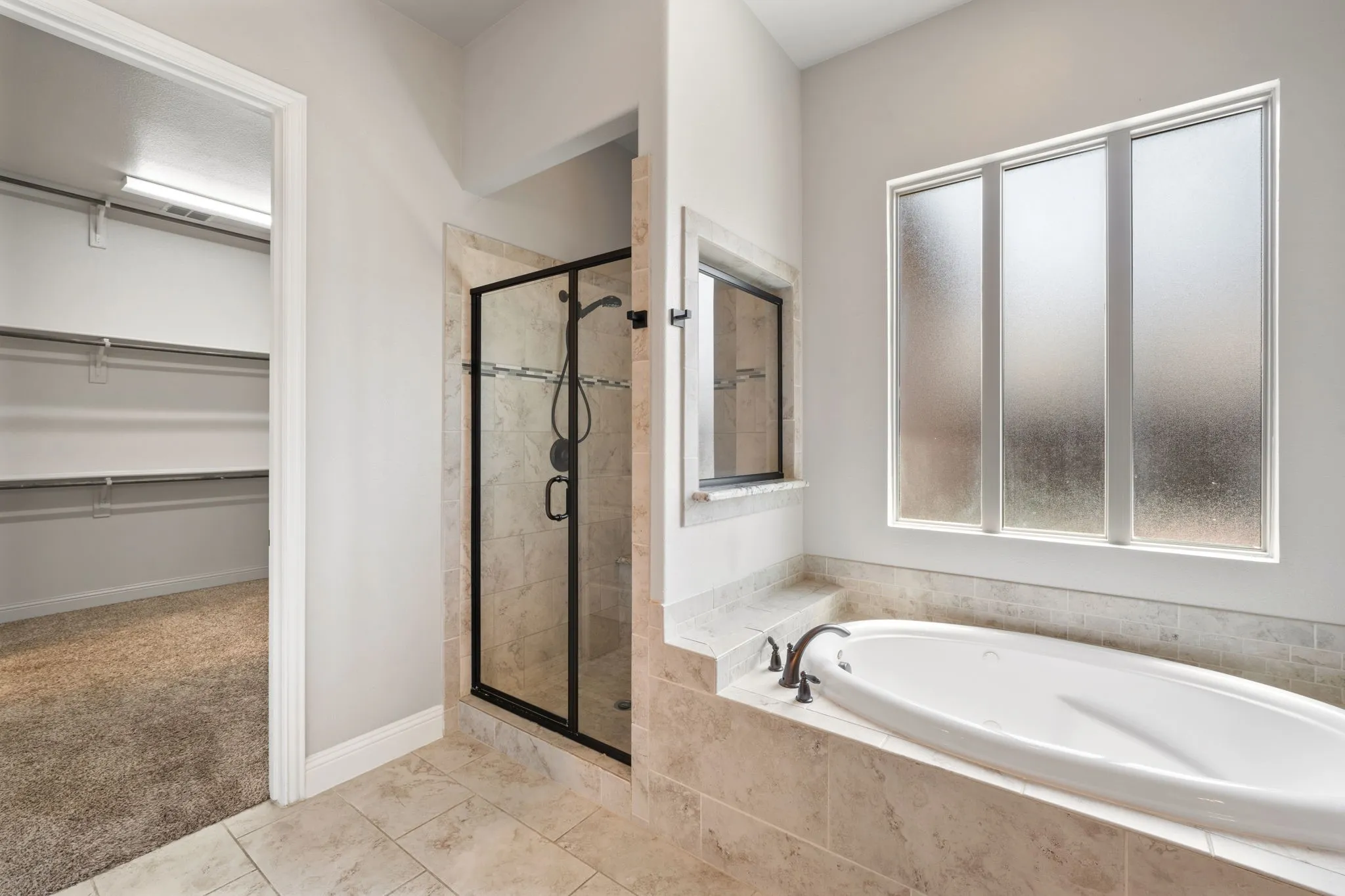 Soaking tub with tile surround, walk-in shower with glass enclosure, tiled flooring, and high ceilings
