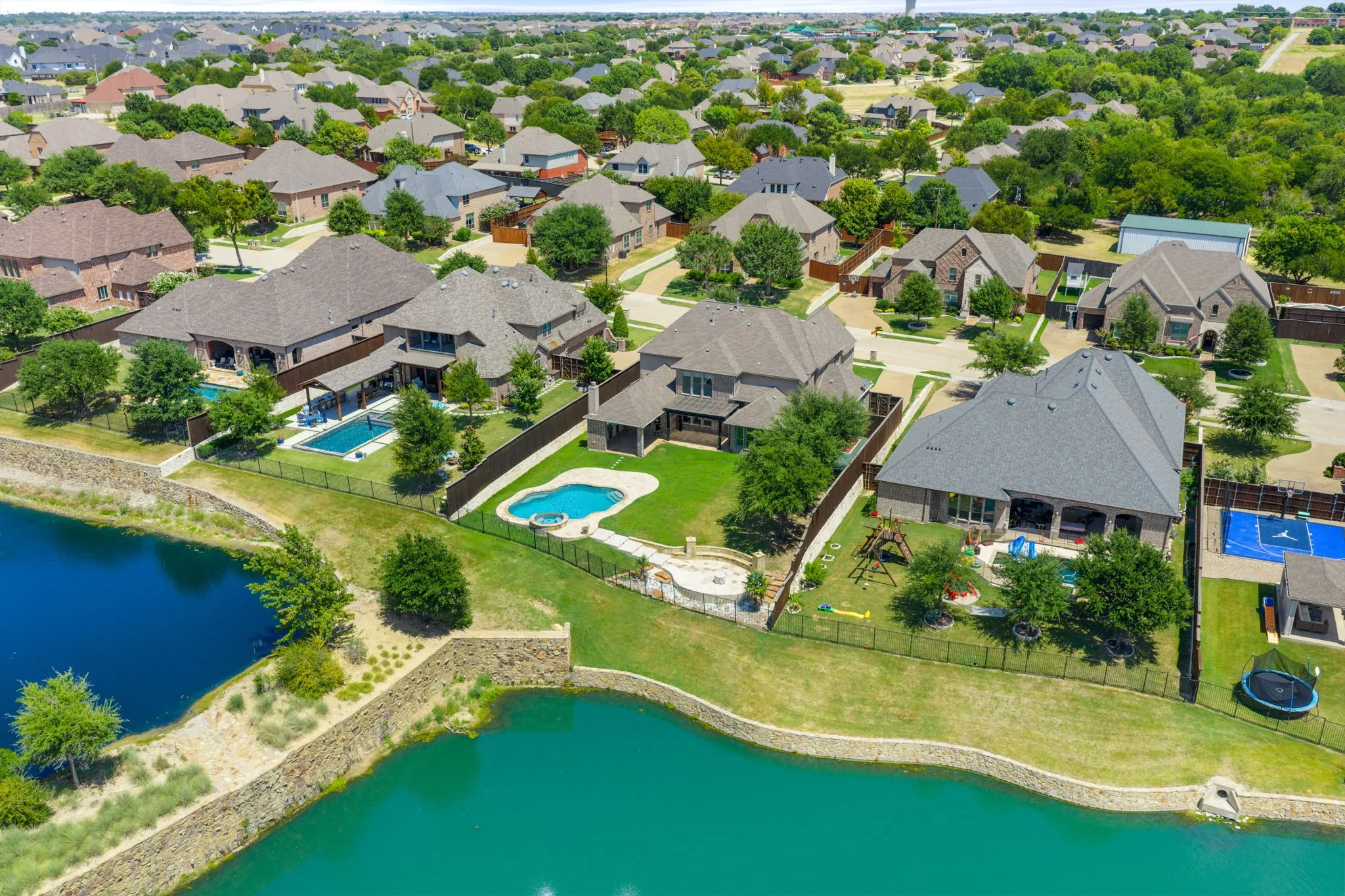 Expansive residential neighborhood with mature trees, multiple properties featuring private swimming pools, and waterfront access