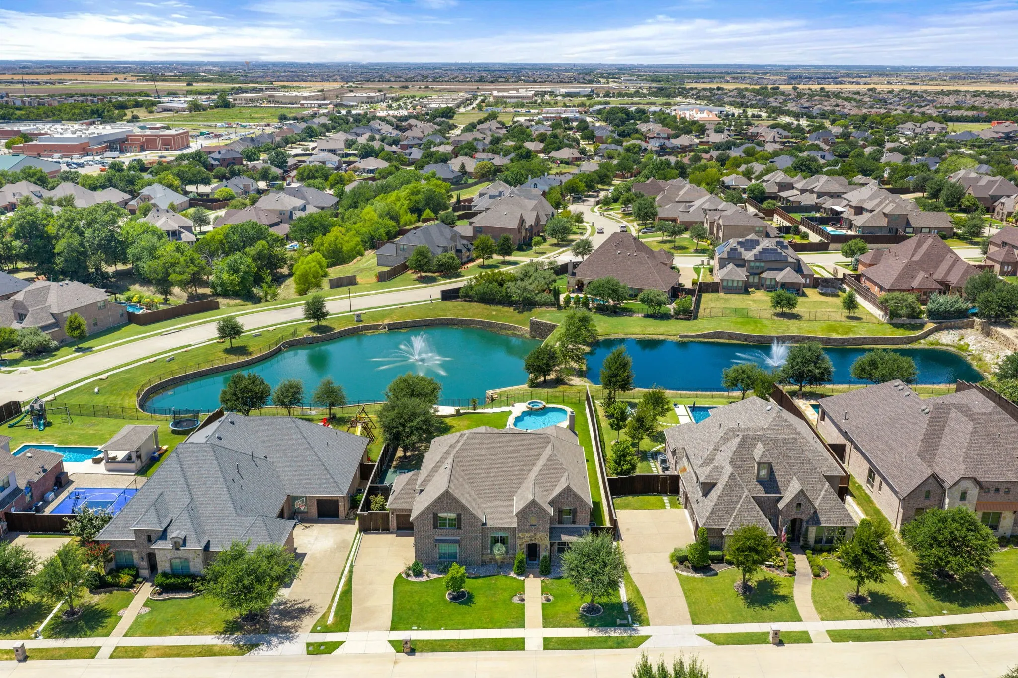 Expansive residential community featuring a prominent pond with water features, numerous private swimming pools, and extensive green spaces