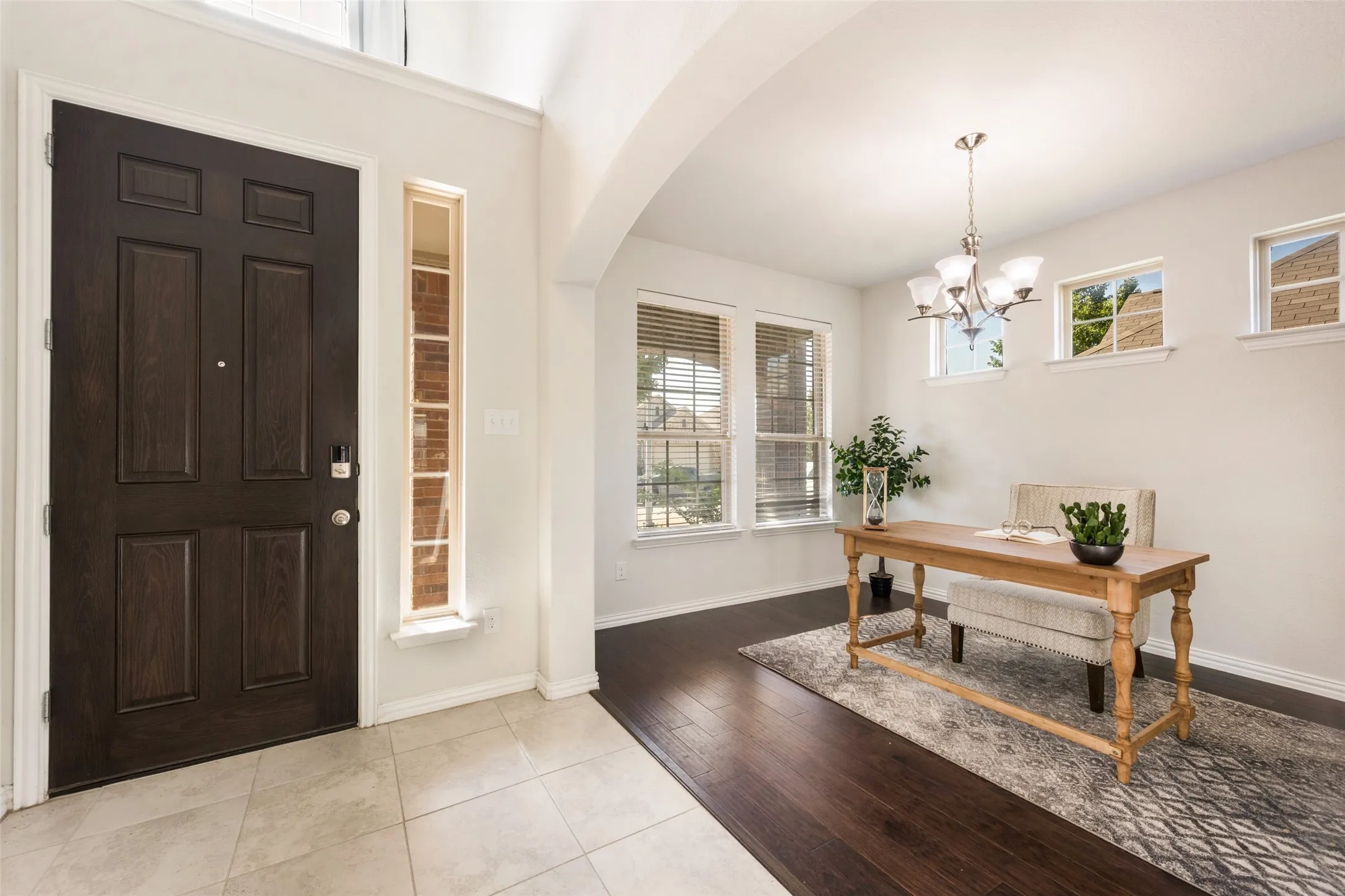 Welcoming foyer featuring a striking six-panel dark wood entry door, light tile flooring, and vaulted ceilings with skylights