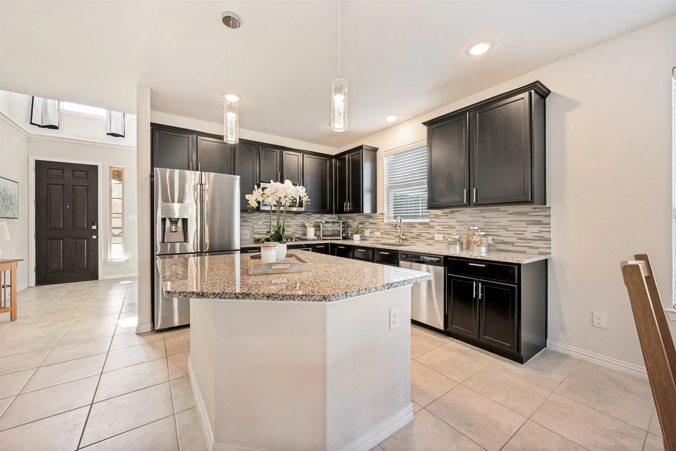 Kitchen featuring dark wood cabinetry, a granite island countertop, stainless steel appliances, and a mosaic tile backsplash