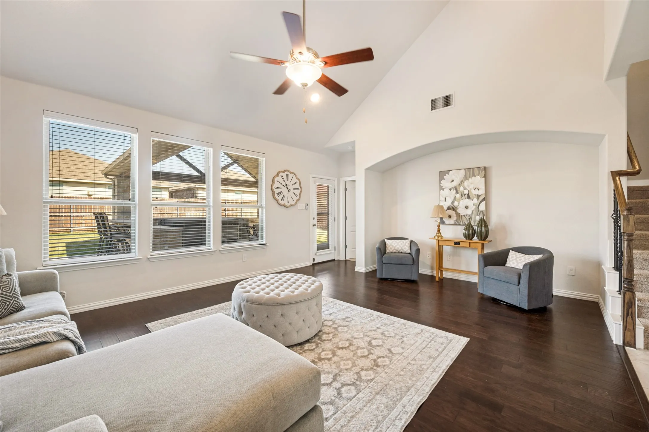 Vaulted ceiling with a ceiling fan, dark wood-finish flooring, and multiple windows