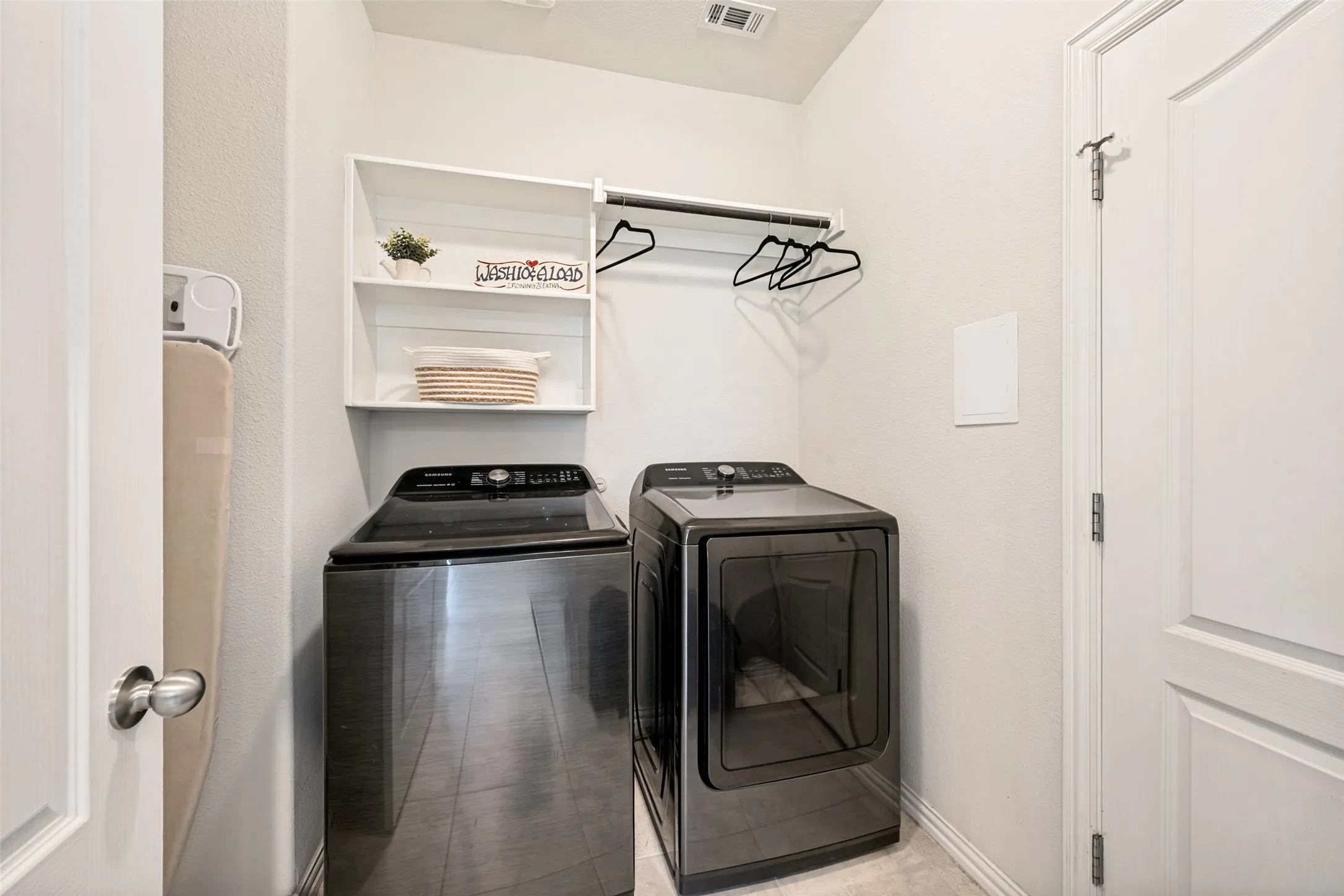 Laundry area featuring built-in shelving, a clothes rod, and light neutral wall paint