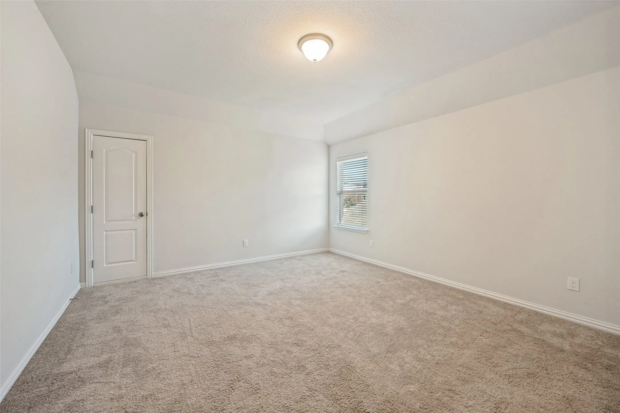 Neutral-toned carpeting, white walls, and a window with blinds