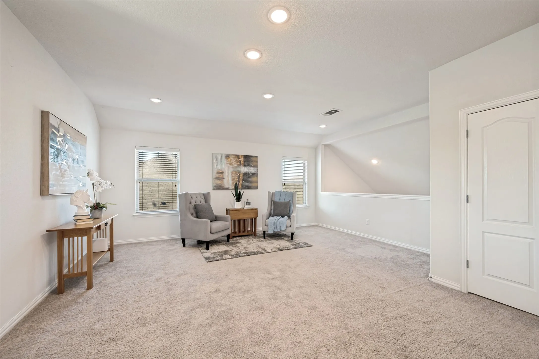 Spacious primary living area with neutral carpet flooring, recessed ceiling lighting, and abundant natural light from multiple windows
