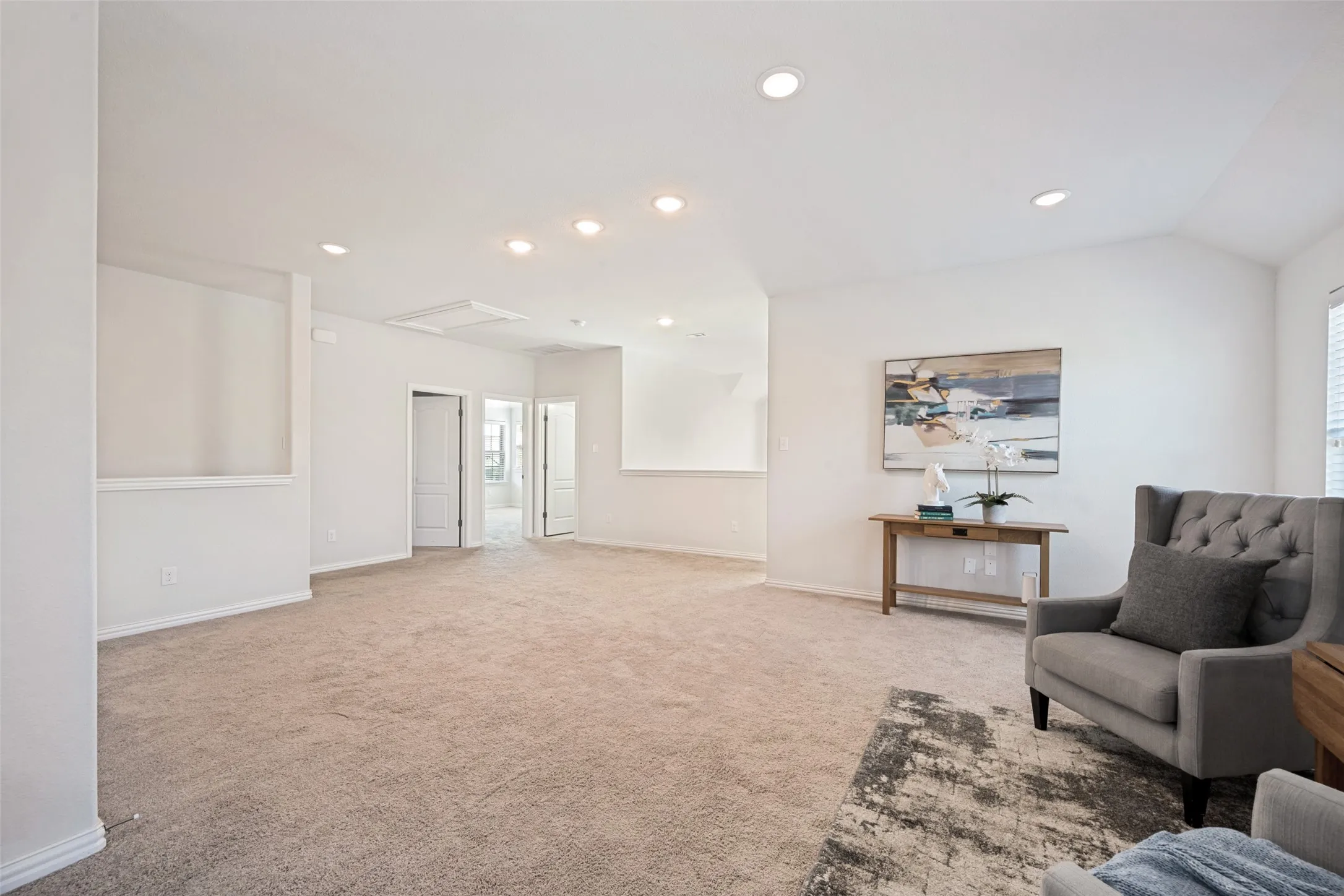 Expansive carpeted area with recessed lighting, multiple doorways, and wall cut-outs