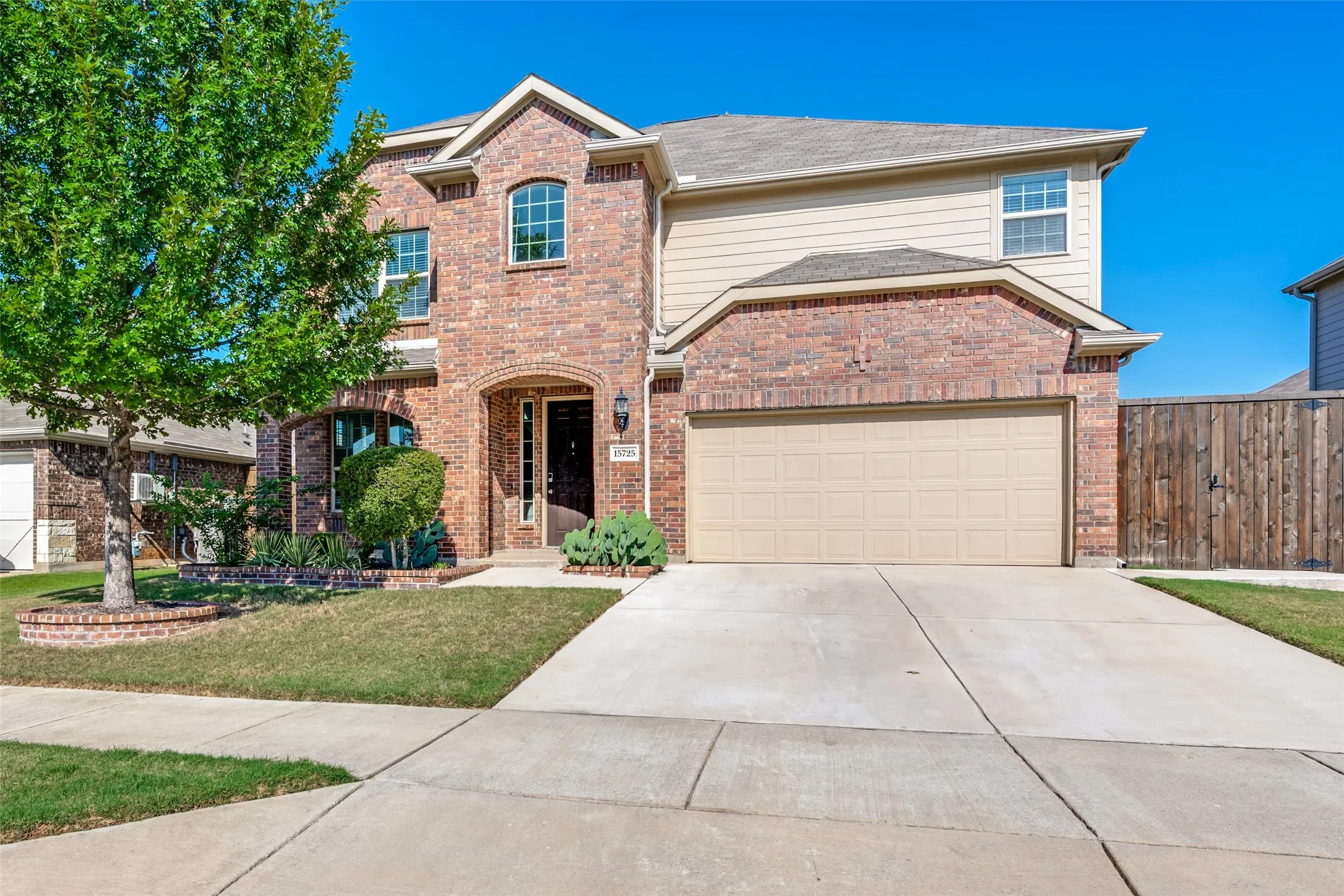 Two-story brick and siding facade with an arched entry, an attached garage, and a concrete driveway