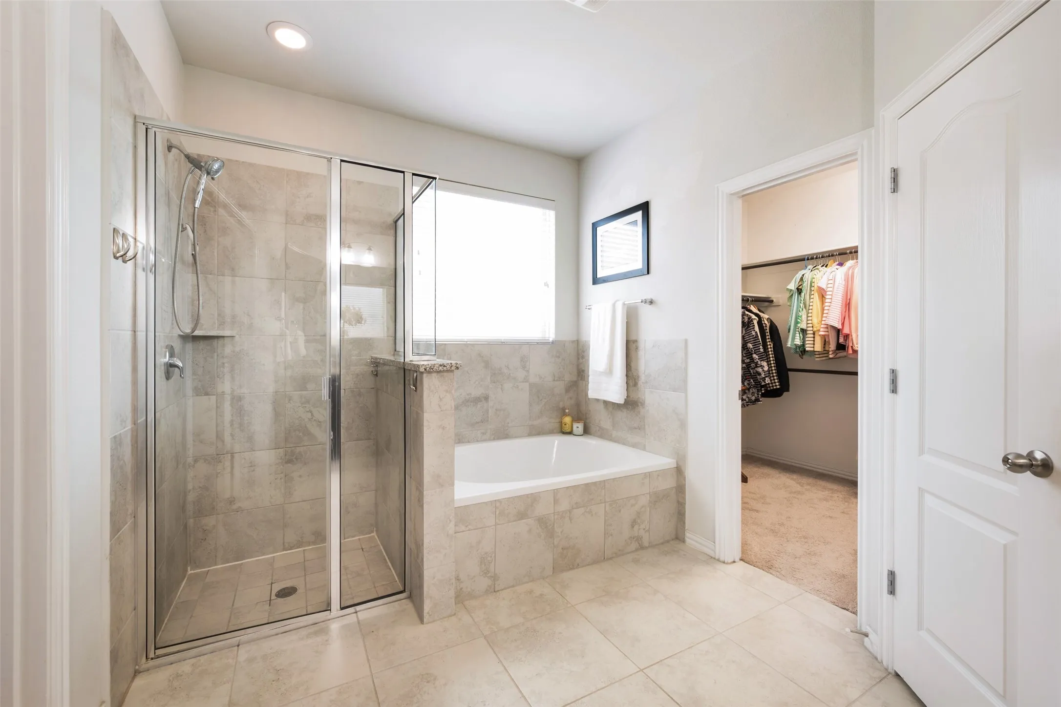 Tiled walk-in shower with glass enclosure, recessed lighting, built-in bathtub, and an adjacent walk-in closet