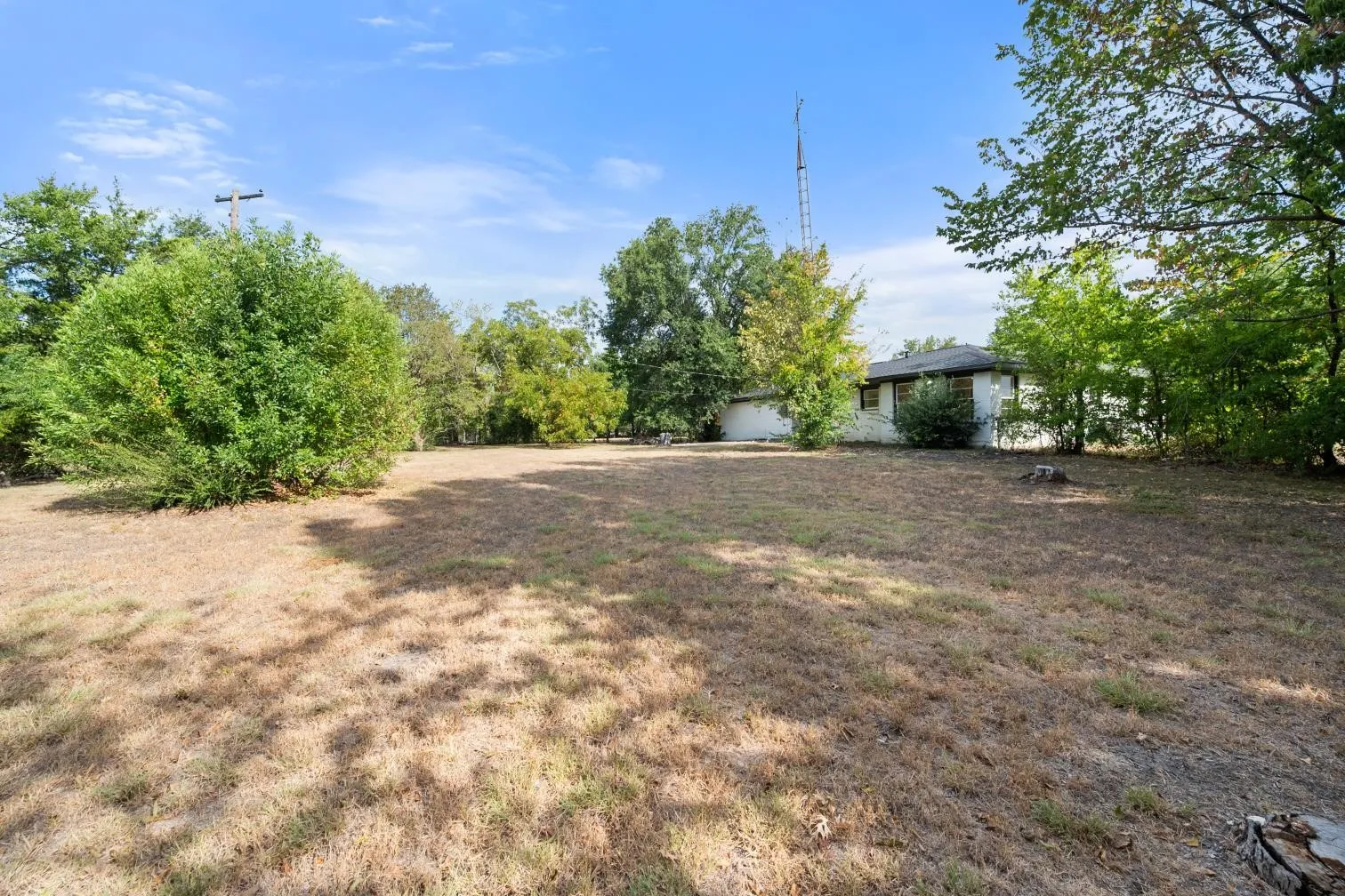 Expansive open lot with mature trees and a single-story residence