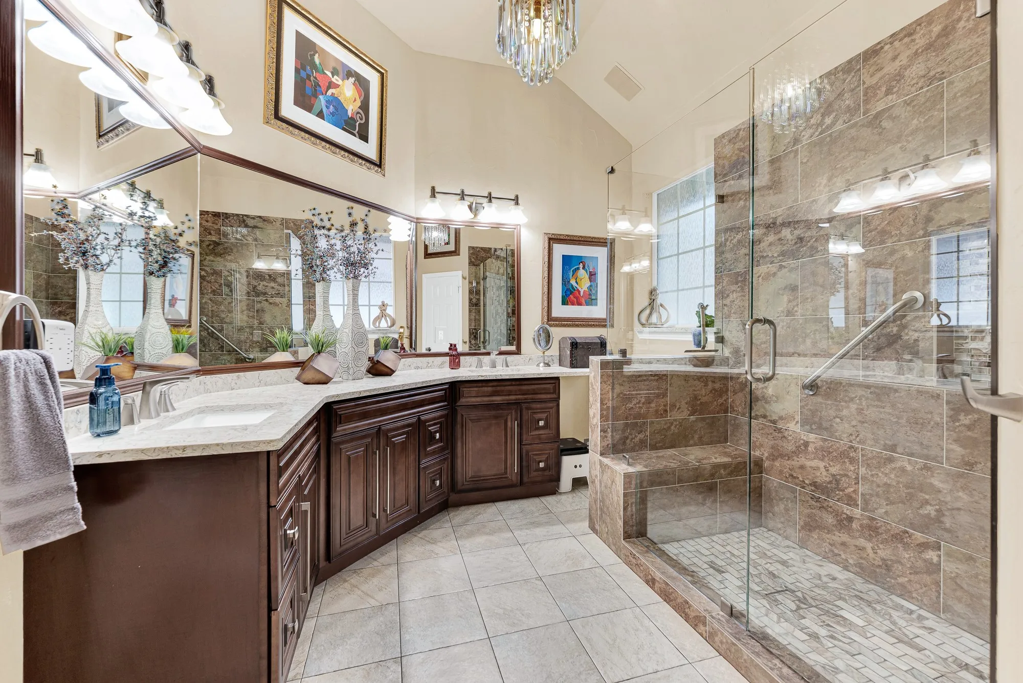 A wrap-around vanity with double sinks offers sprawling counter space under crisp vanity lighting and an elegant central light fixture. Visualize effortlessly getting ready side-by-side without bumping elbows during peak morning hours.