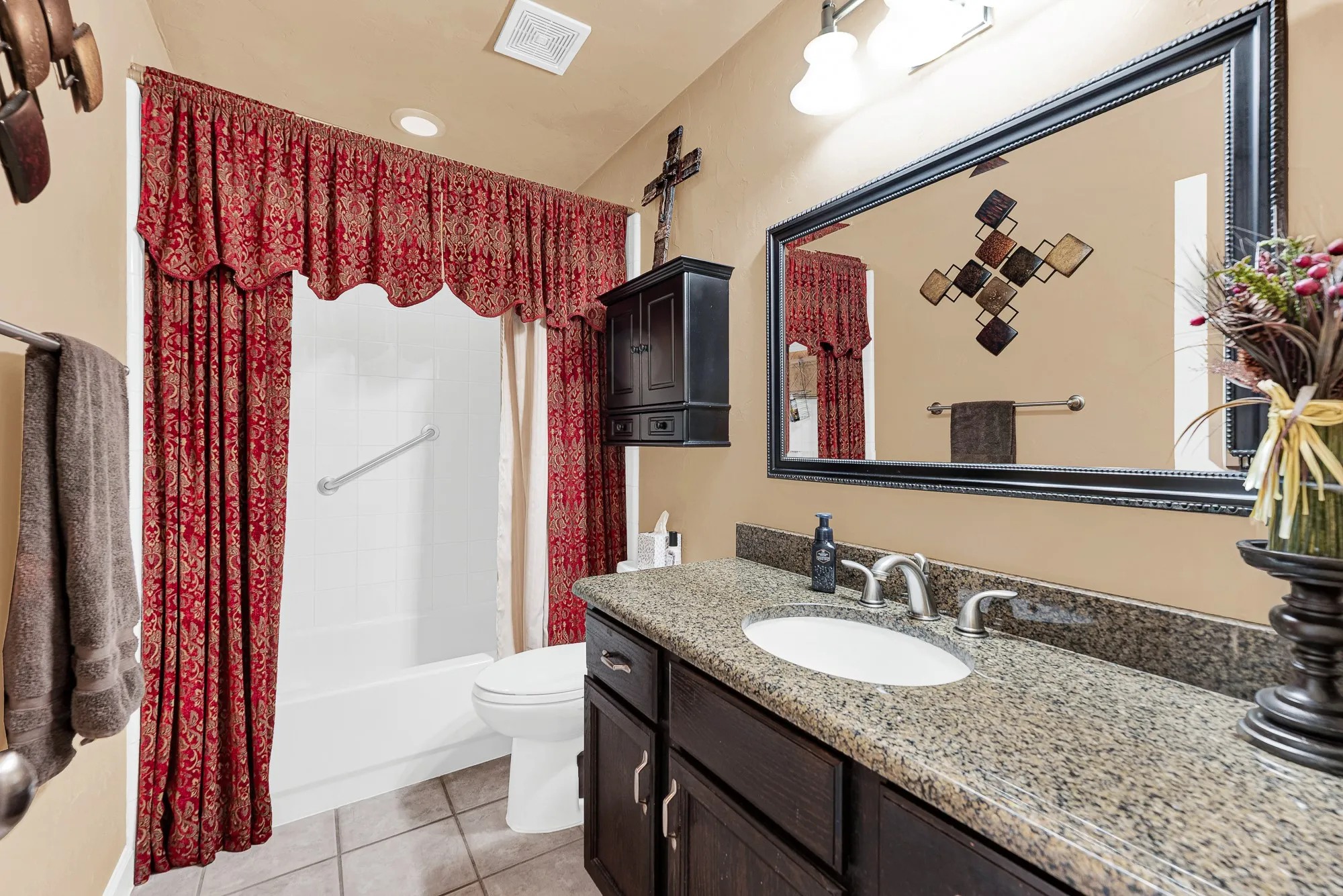 A spacious stone-topped vanity paired with bright overhead sconces provides a functional, well-lit layout. Imagine family members or weekend guests comfortably preparing for the day at their own unhurried pace.