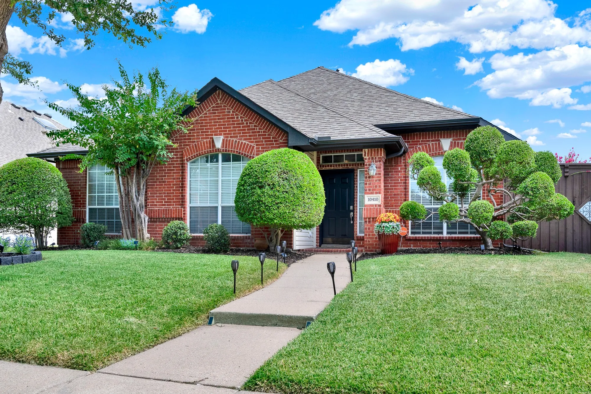 A central walkway guides the eye toward arched brick window details and a welcoming entryway. Picture greeting friendly neighbors on sunny weekend afternoons while enjoying the warm neighborhood breeze.