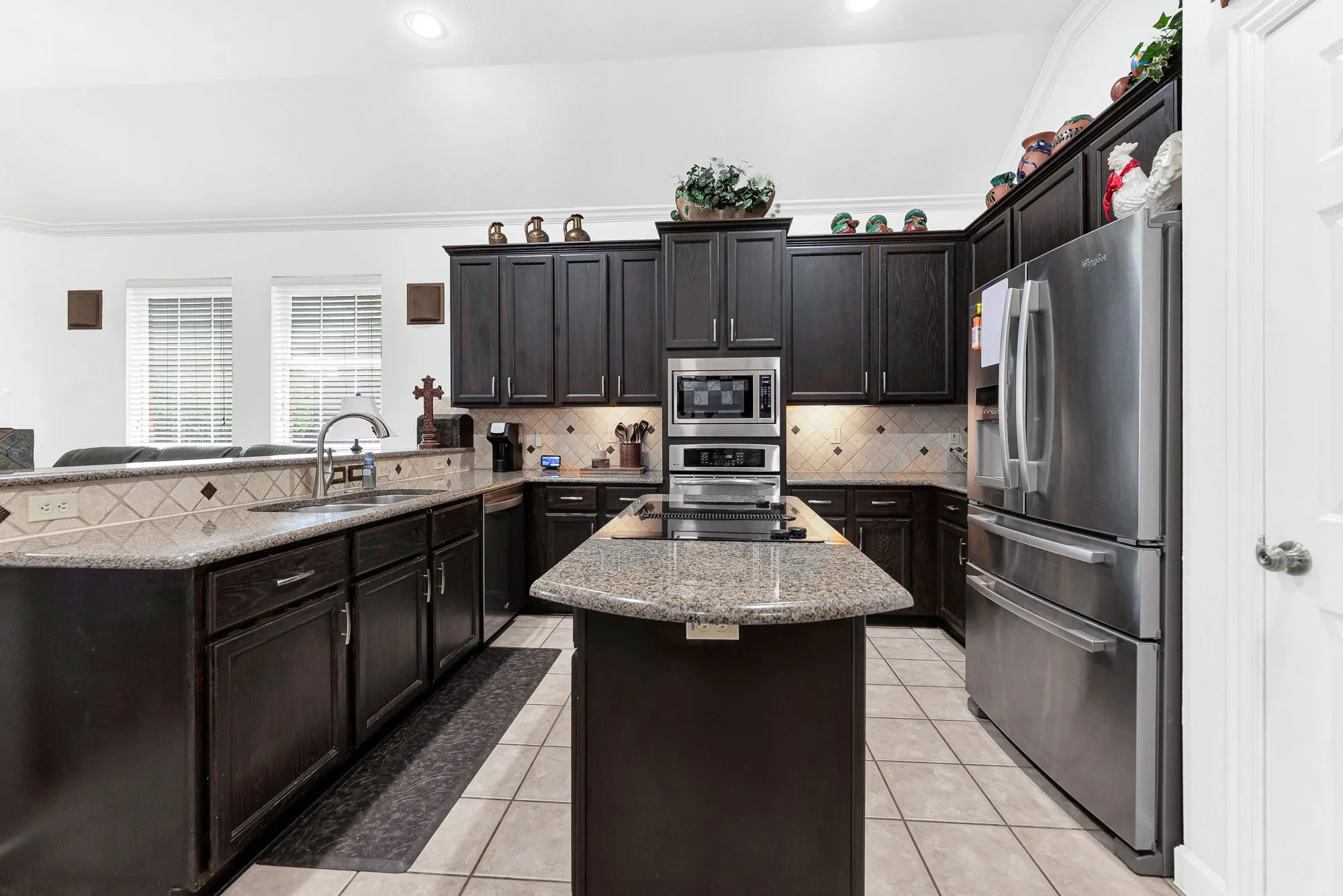 A central prep island grounds the workspace, catching natural light streaming through the adjacent window bank. Imagine rolling out homemade pizza dough while catching up with loved ones around the counter.