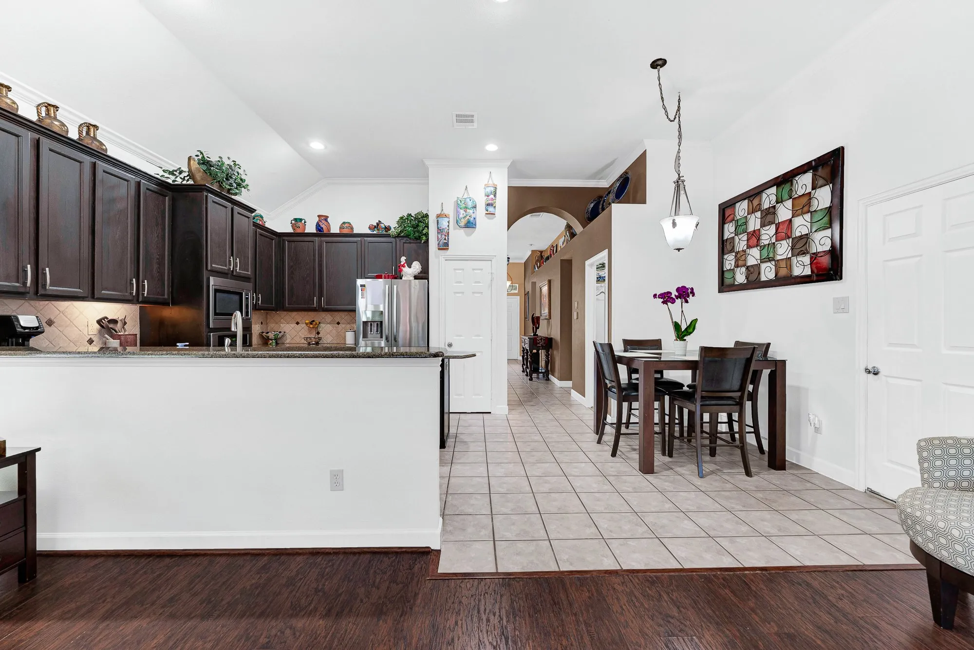 An open tiled hallway transition blends seamlessly with deep cabinetry under high angled ceiling lines. Imagine gathering around the breakfast nook for easy weeknight dinners with loved ones.