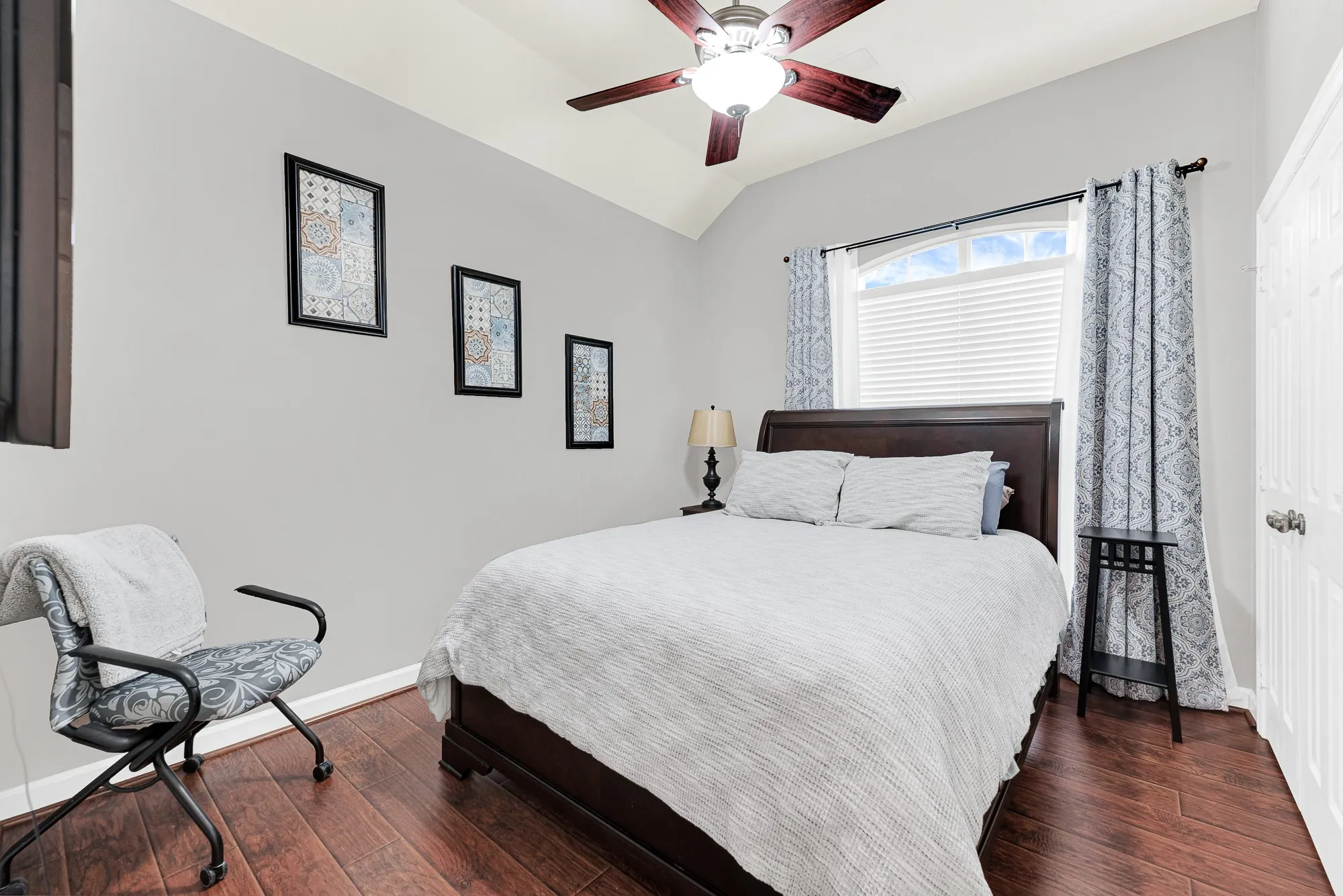 A high arched window draws gentle morning light deep into the serene room. It’s an inviting, quiet sanctuary where visiting guests can recharge in comfort after a long journey.