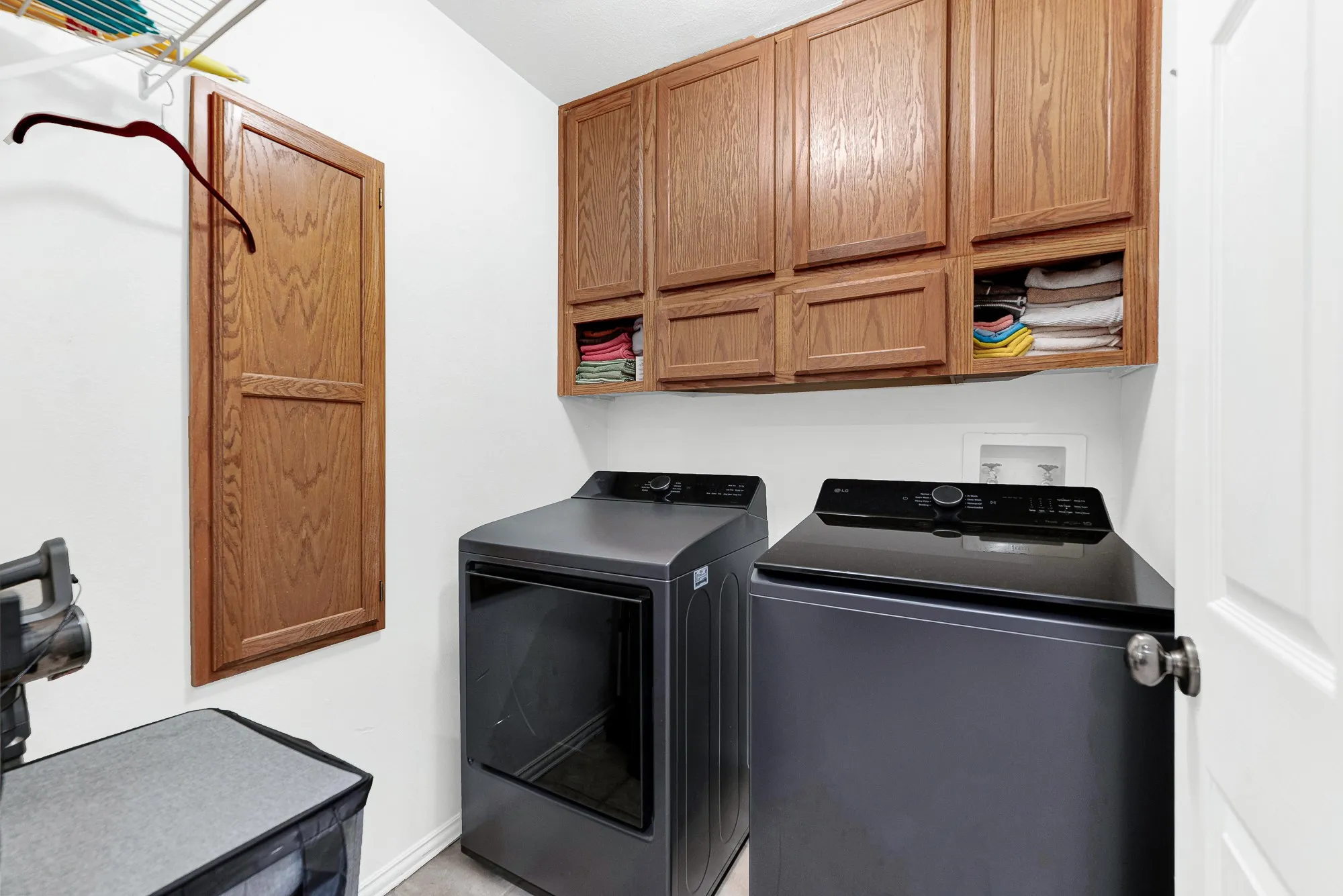 Generous wall-mounted oak cabinetry maximizes vertical storage space above dedicated appliance nooks. Visualize making quick work of daily household chores in an organized, efficient space.
