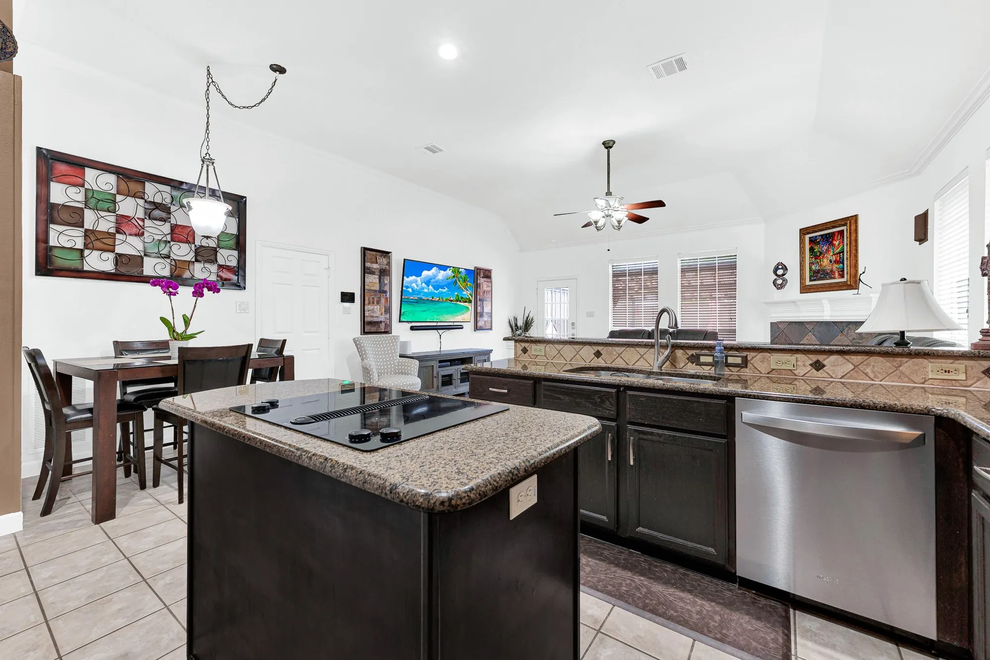 A tiered stone-topped breakfast bar creates a subtle divider between the cooking zone and dining nook. Picture serving hot morning pancakes straight from the cooktop to eager kids waiting nearby