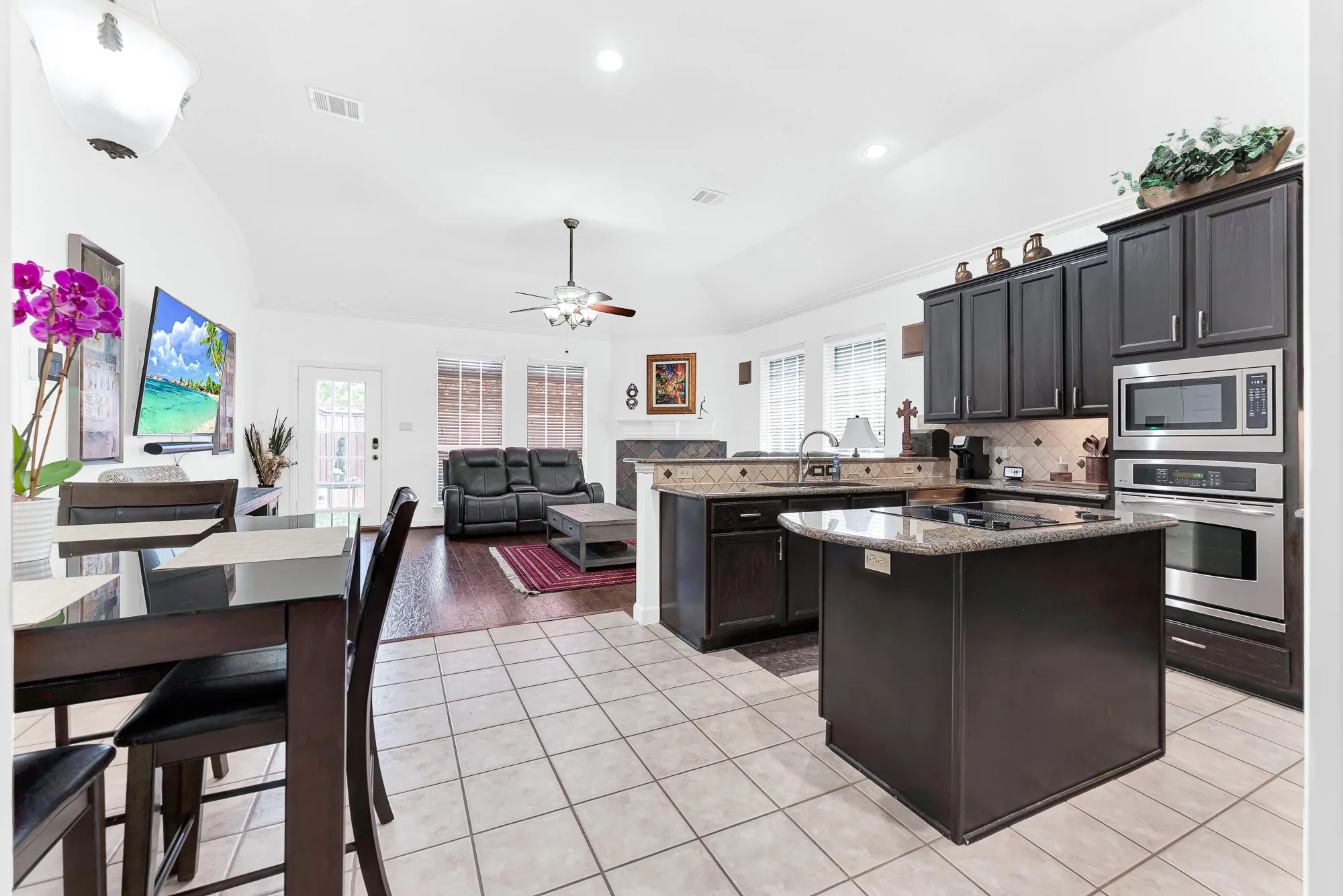 High vaulted ceilings sweep over the open layout, bouncing soft ambient light across the tile flooring. It’s ideal for chatting with family in the living room while prepping weeknight meals