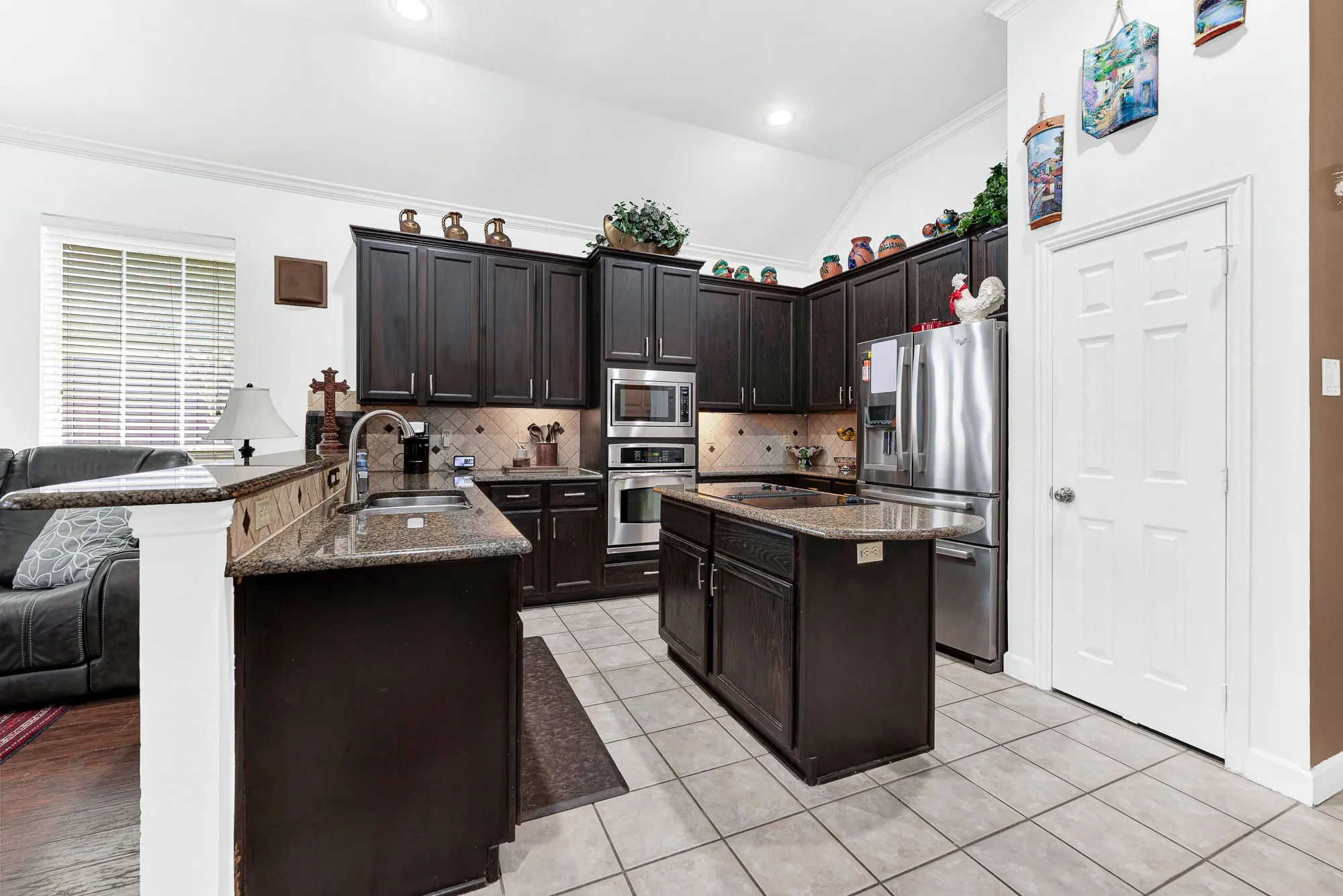 Deep espresso cabinetry stretches upward, offering rich vertical depth and abundant storage beneath recessed lighting. You can easily picture whipping up your favorite weekend brunch with everything right at your fingertips.