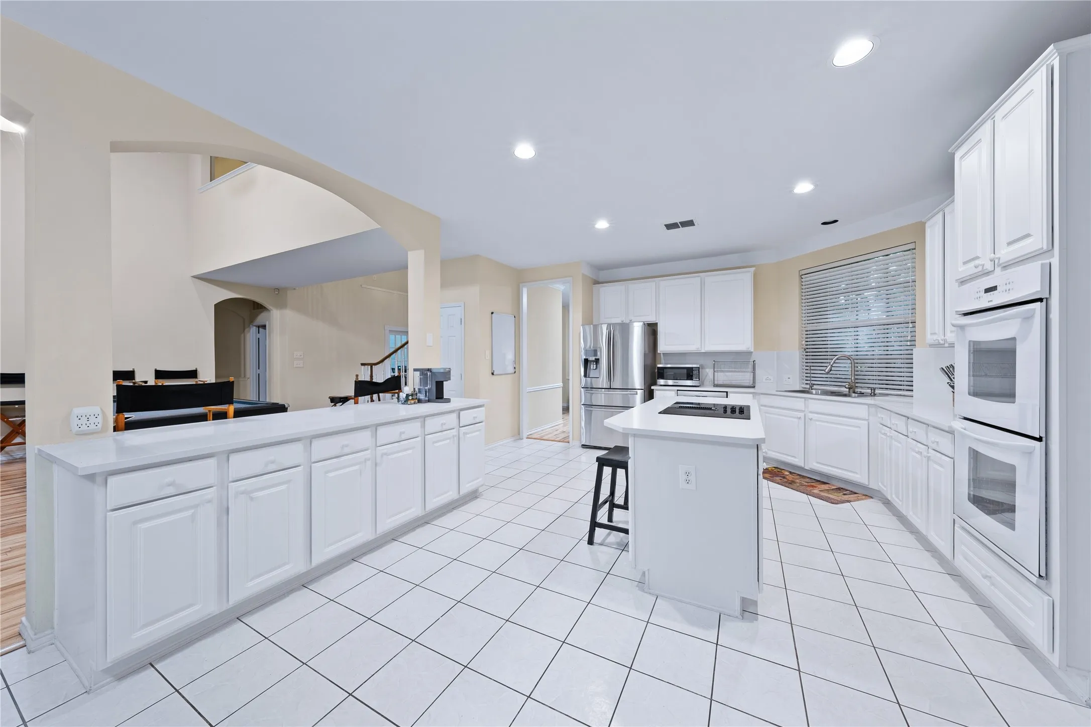 Kitchen featuring white cabinetry, white countertops, stainless steel appliances, a center island, and tiled flooring