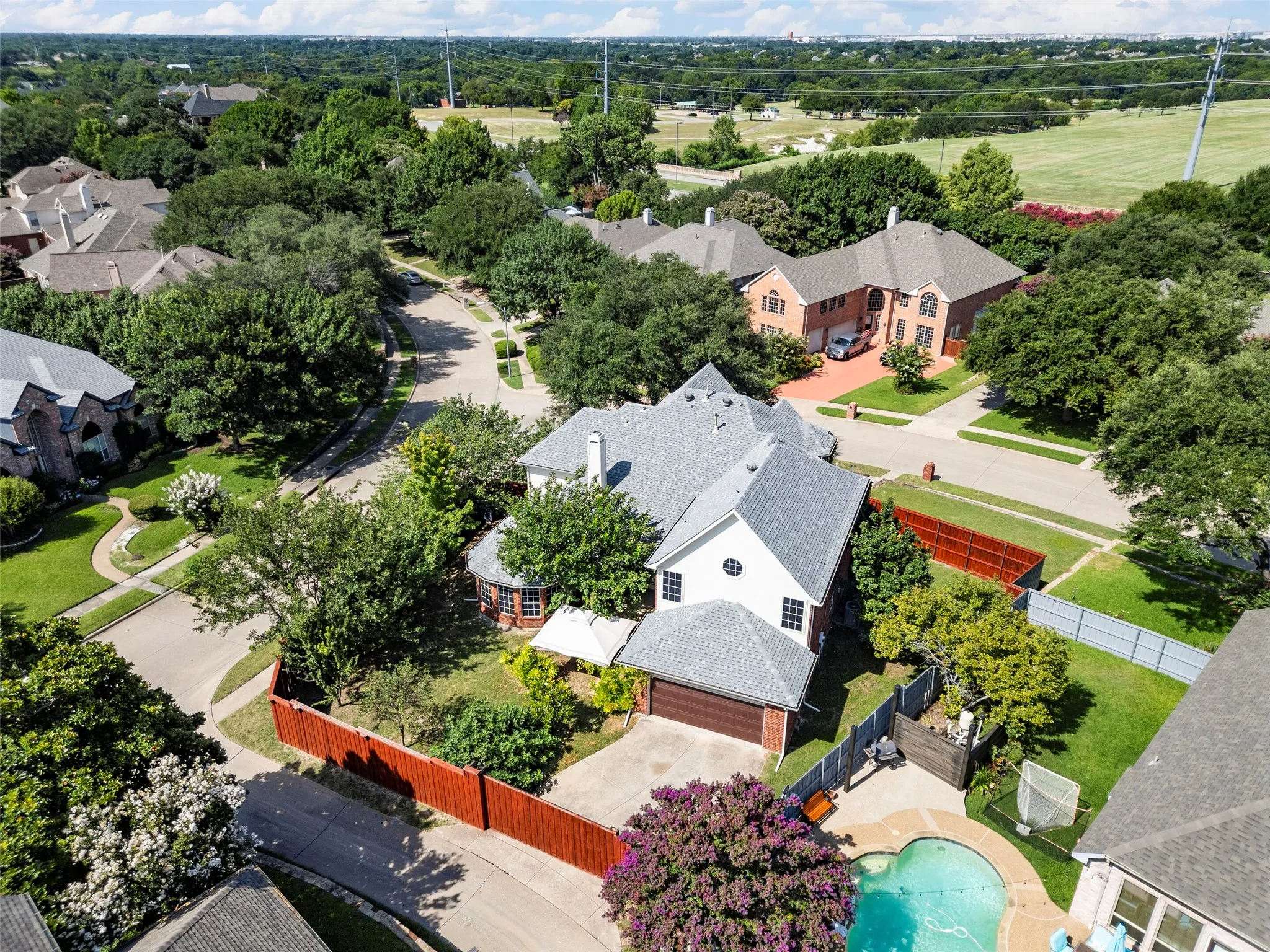 Aerial perspective showcasing a residential area with mature trees, paved streets, and residential architecture