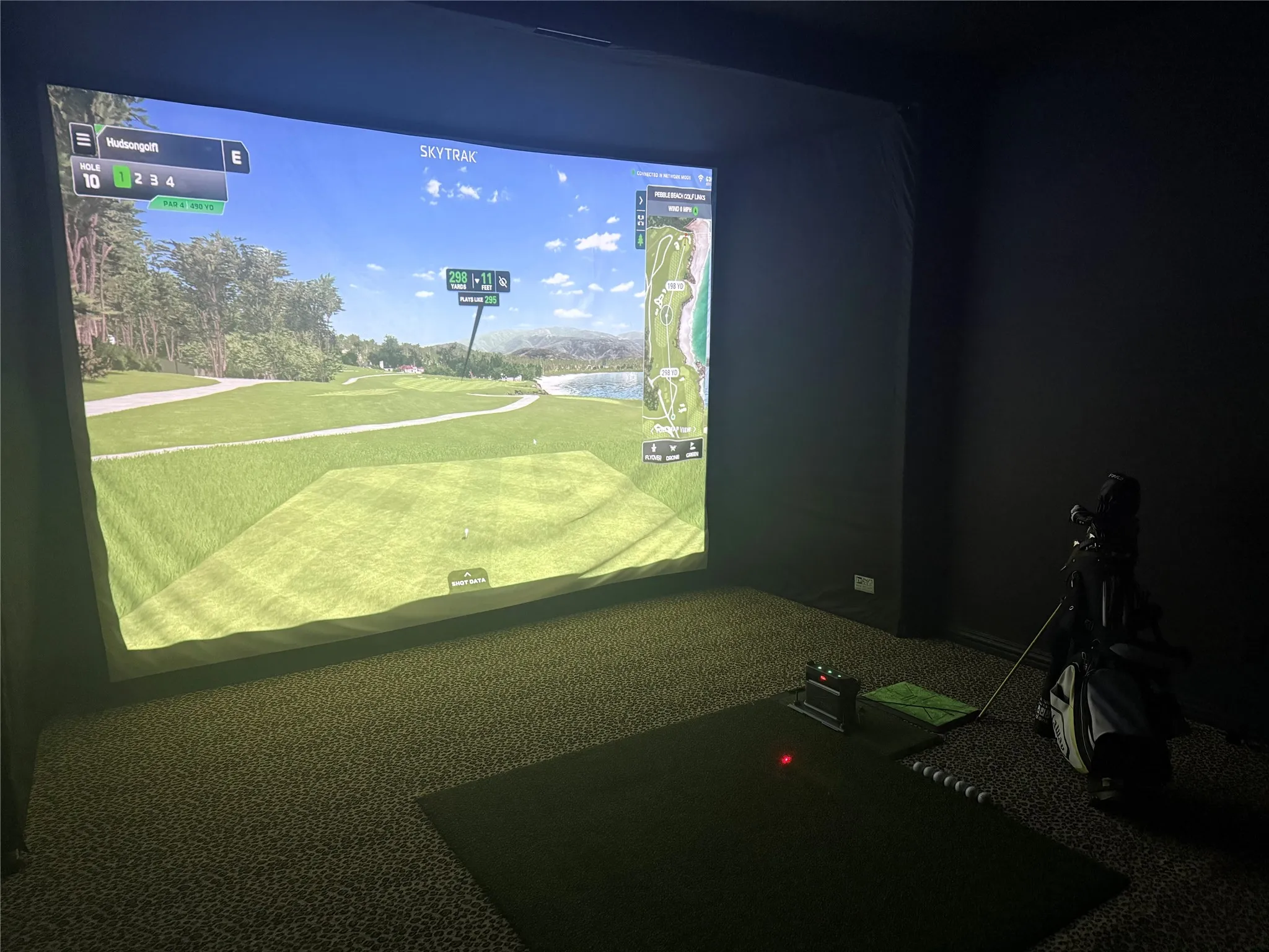 Golf simulator with projector screen and dark wall coverings