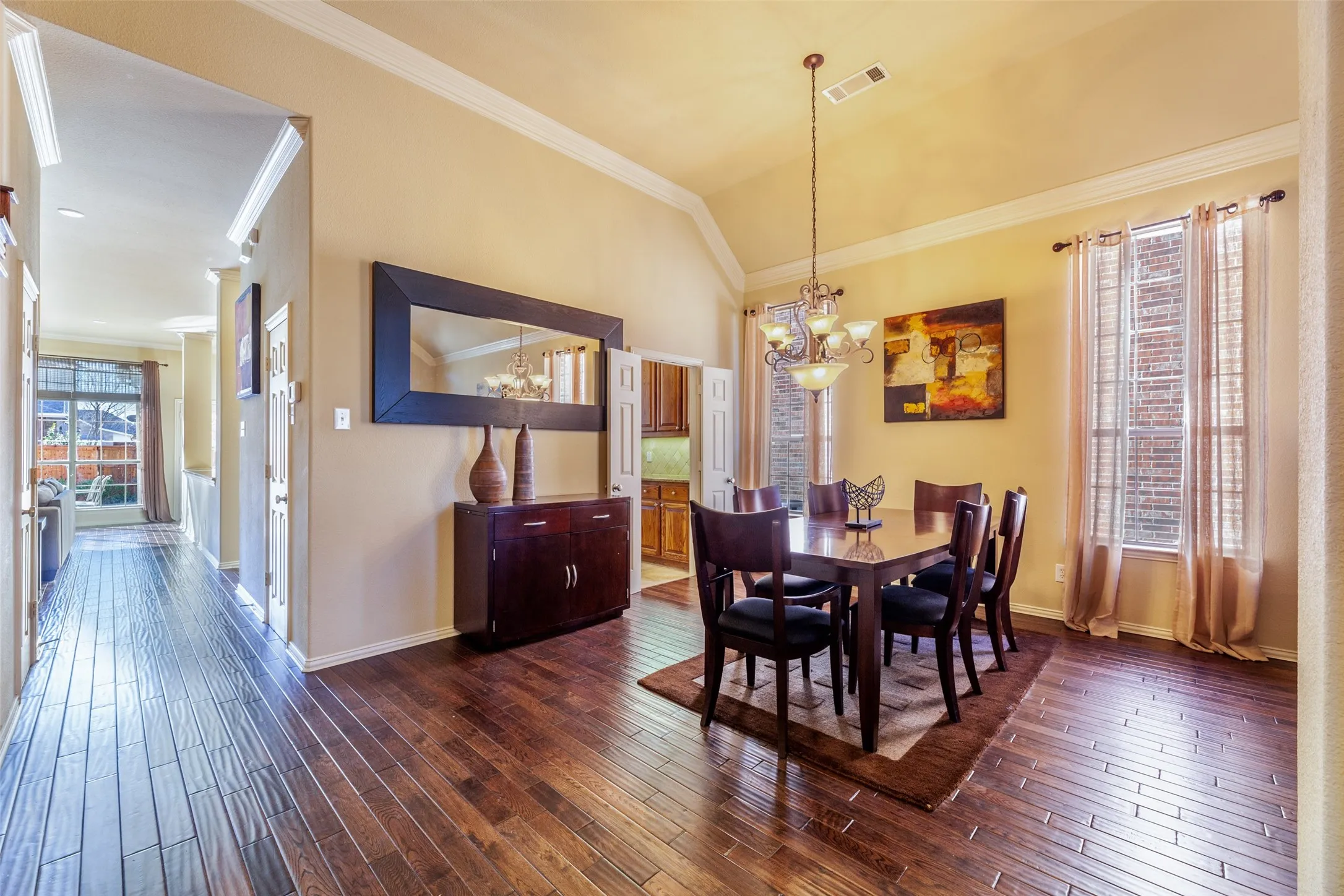 Dining room featuring baseboards, an inviting chandelier, visible vents, crown molding, and dark wood-type flooring