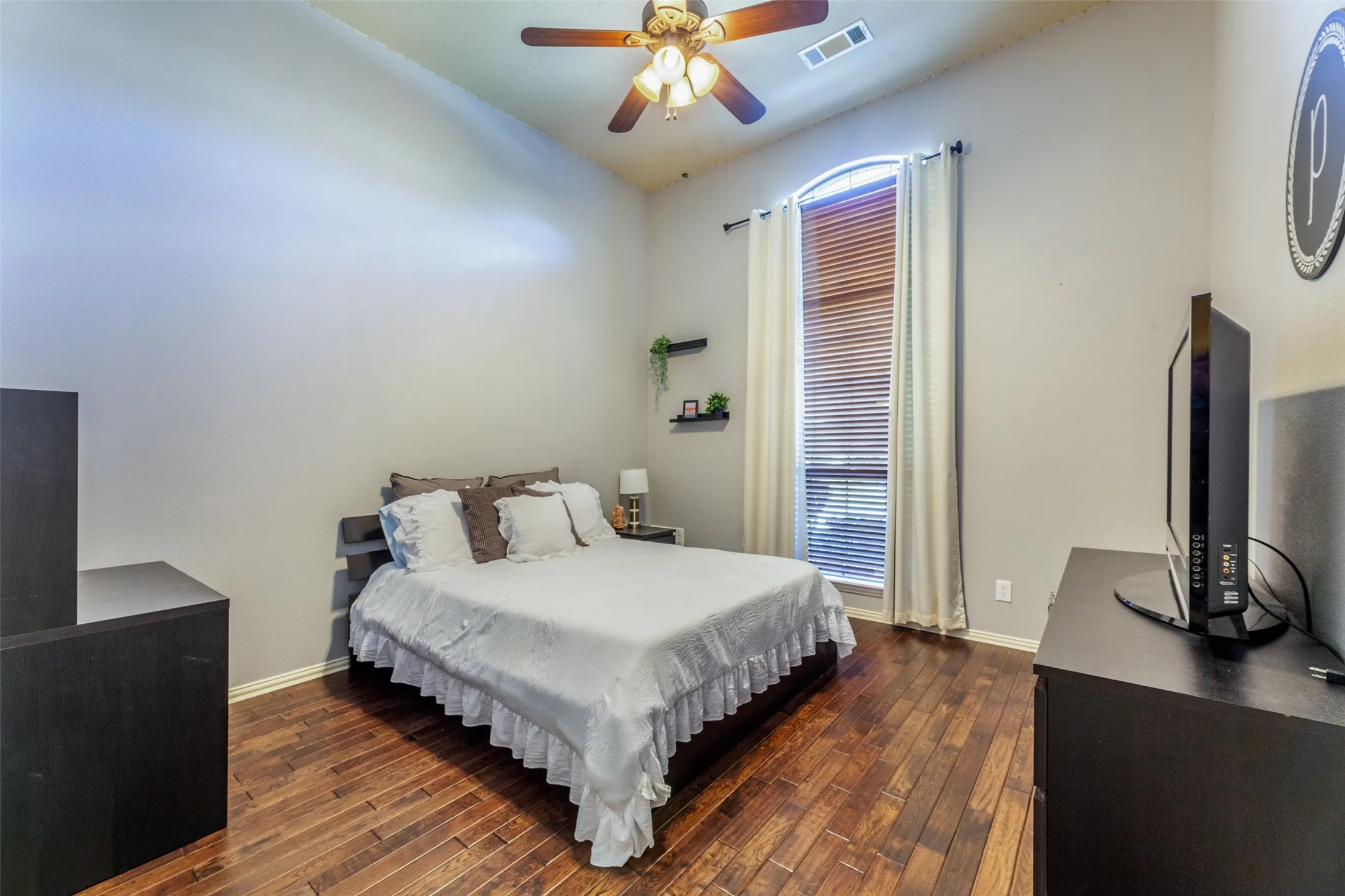 Bedroom featuring multiple windows, visible vents, baseboards, lofted ceiling, and dark wood-style floors