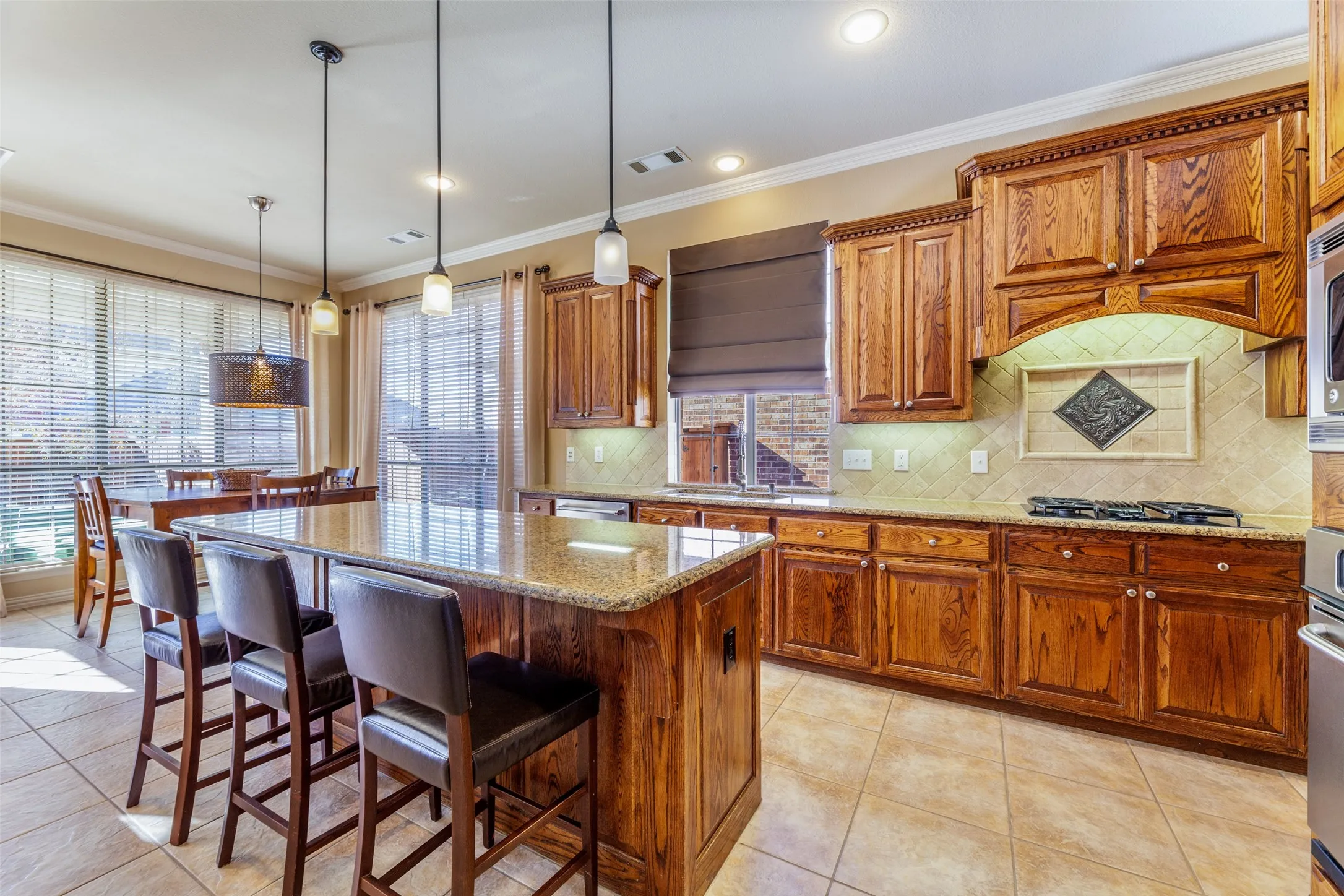 Kitchen featuring ornamental molding, visible vents, a kitchen bar, light stone countertops, and appliances with stainless steel finishes
